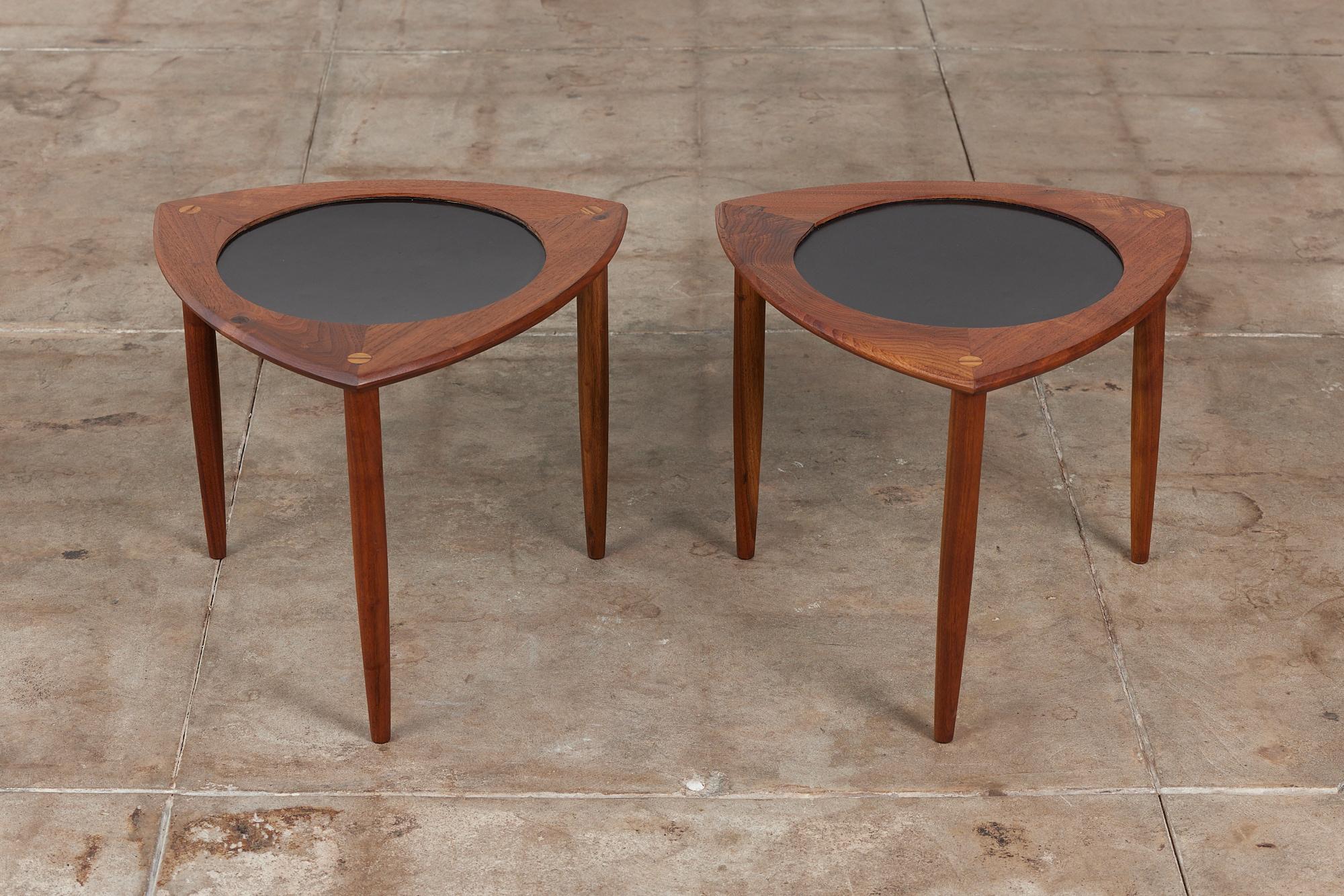 Pair of walnut side tables have a triangular “guitar pick” shape and three tapered dowel legs. The center of each table has a circular black laminate inlay and varying wood gain.

Dimensions
18.75