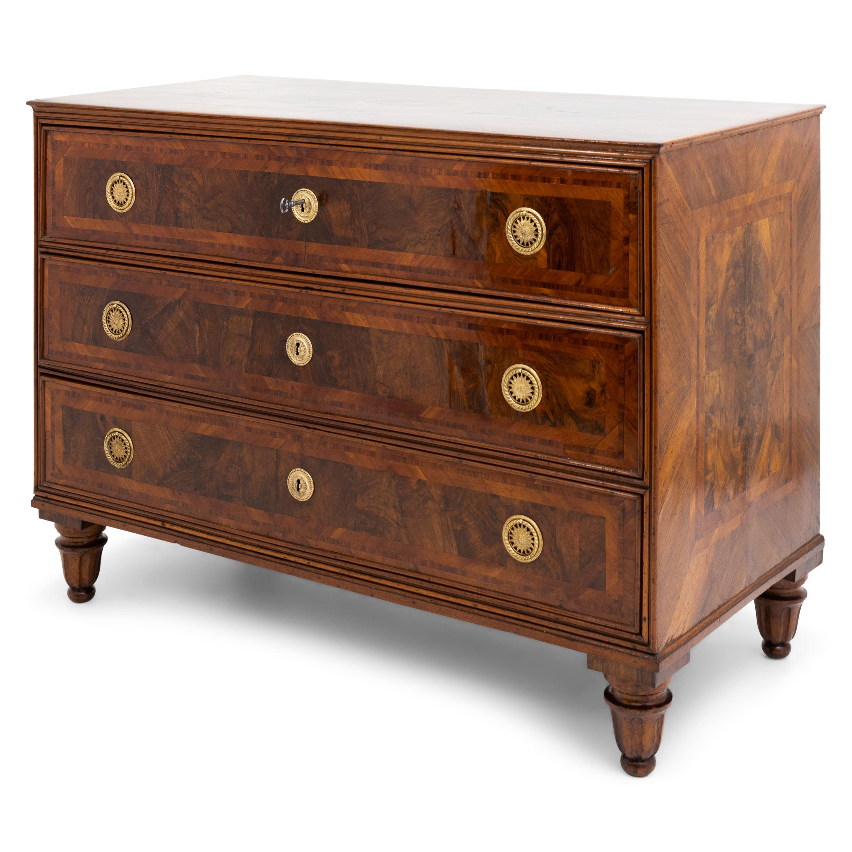 Pair of Louis Seize chests of drawers on baluster feet with three drawers and profiled trusses in walnut veneered. The disc-shaped fittings with rosette decoration and ring-shaped handles are fire-gilded. The chests of drawers have been expertly