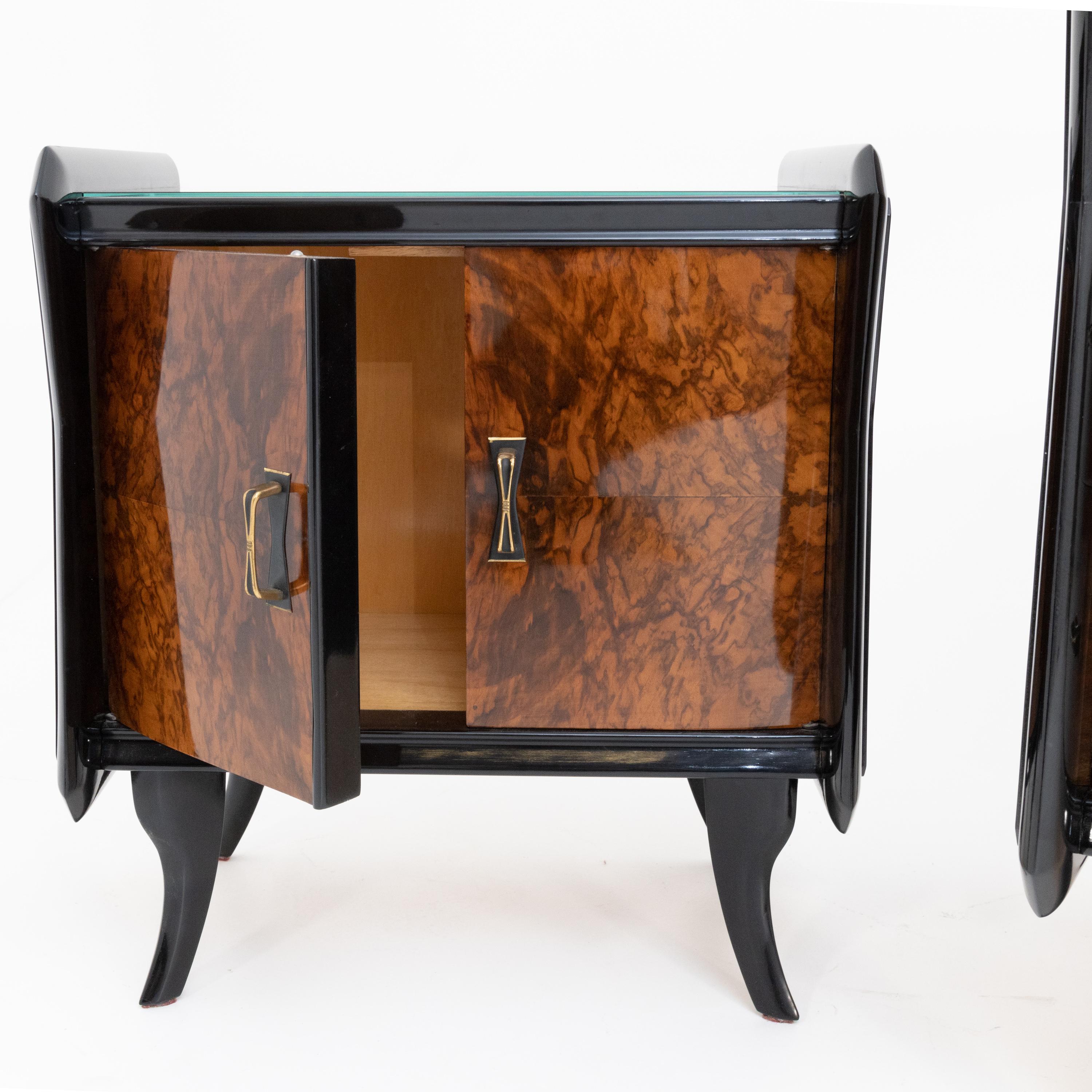 Pair of Italian nightstands with two doors. The body stands on slightly flared legs, is partly ebonized and shows a very nice walnut veneer on the front. The handles are X-shaped and made of brass.
   