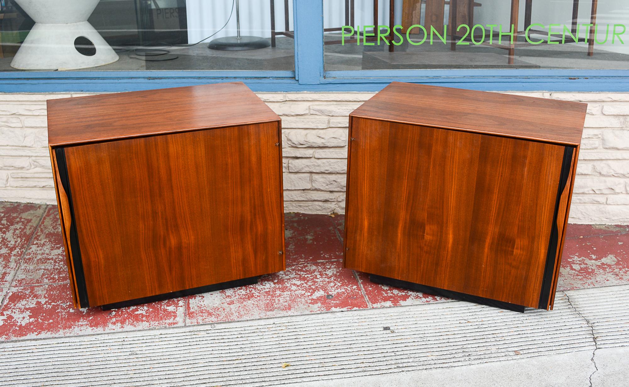 Pair of walnut nightstands designed by John Kapel for Glenn of California. These feature  a book or magazine holder on the inside of a large single door. The inside has one adjustable shelf. There is a pull out shelf in the top of the inside. It has