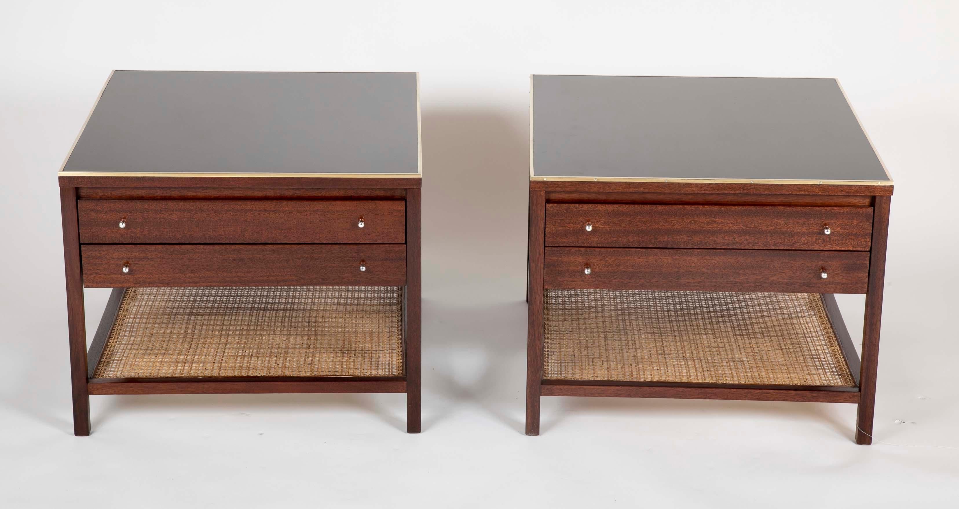 Pair of walnut Paul McCobb side tables with black leather tops, brass trim and caned lower shelf, 1960s.
