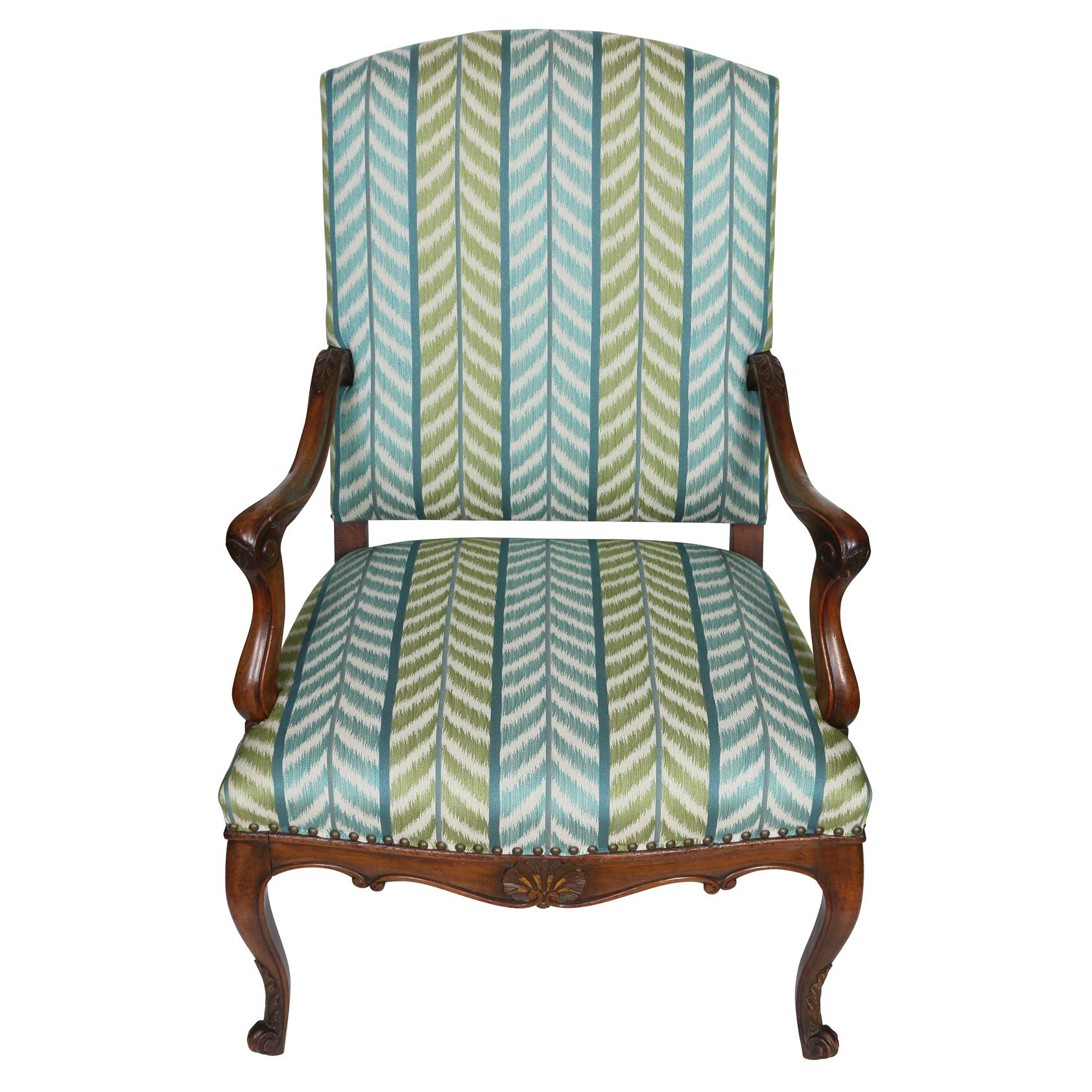 A pair of walnut Regence style chairs newly upholstered with Quadrille fabric in a blue and green chevron print.  The upholstered fauteuil chairs are finished with nail head trim to the seat. The arms and cabriole legs are beautifully carved with a