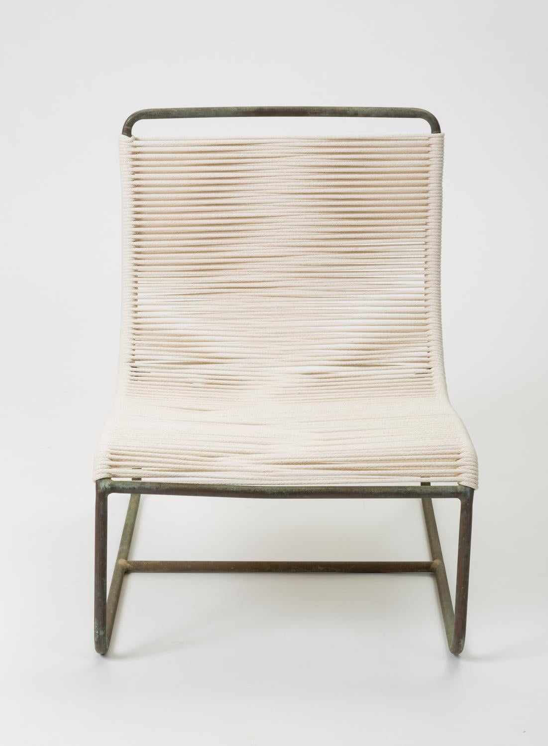 A pair of low lounge chairs, known as the “Sleigh Chair” by Walter Lamb for Brown Jordan. A continuous length of tubular bronze serves as the frame of a scooped seat, bends beneath the chair to form two runners, and terminates in two delicately