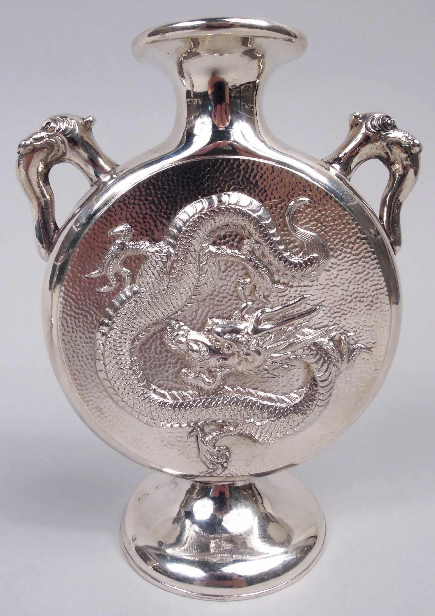 Pair of Chinese export silver vases, ca 1910. Each: Flat and round moon body on domed foot; animal-head handles mounted to shoulder. On front and back is chased dragon—a horned and taloned serpentine serpent on hand-hammered ground. Marked Wang Hing