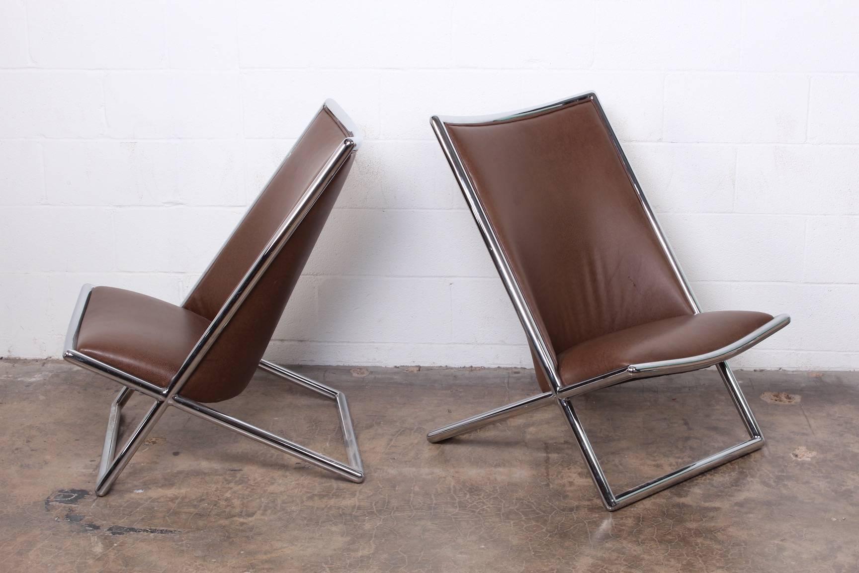 A pair of Ward Bennett scissor chairs upholstered in brown leather.
