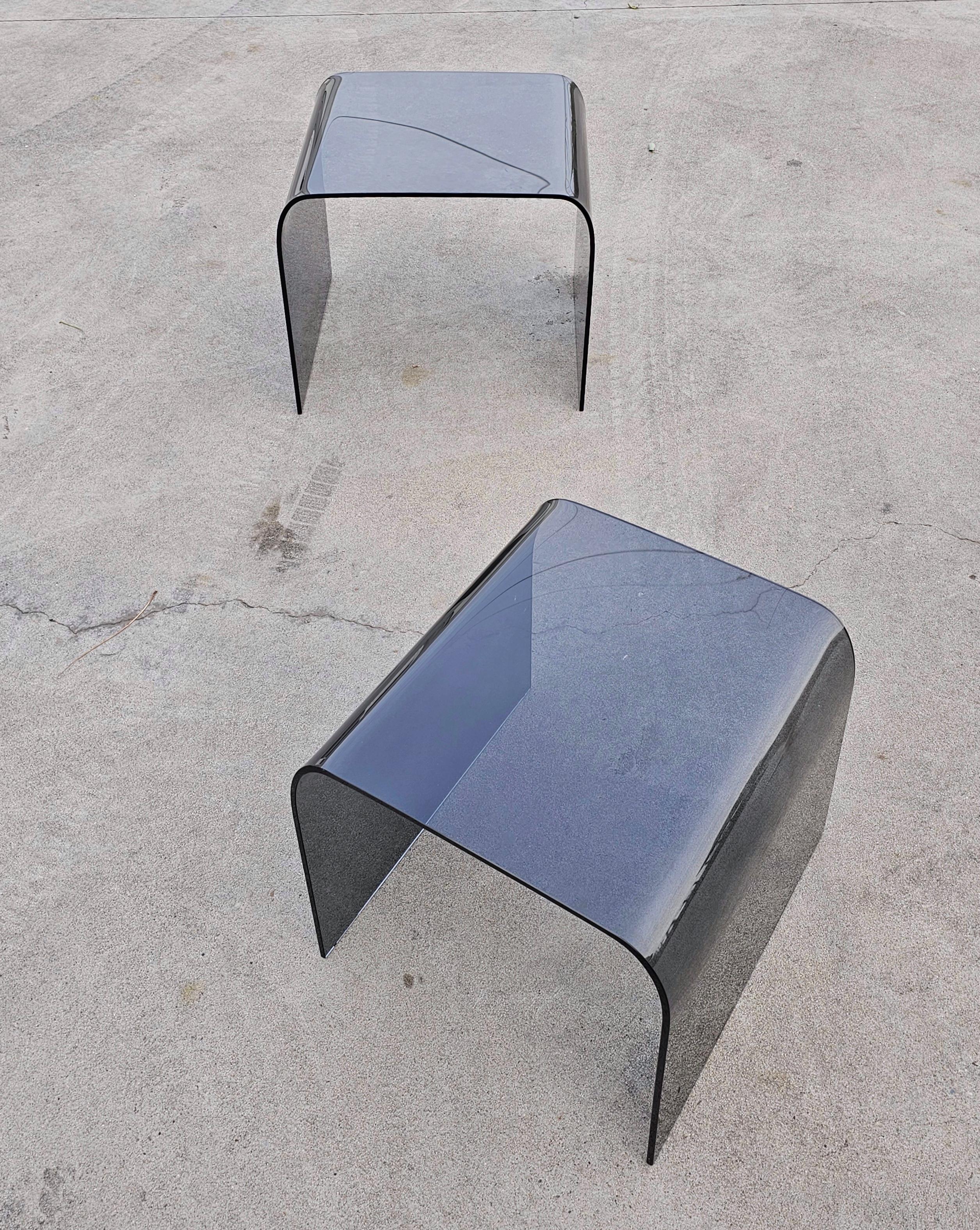 In this listing you will find a pair of Waterfall Nesting Side Tables attributed to Fiam. They are made of tinted, gray glass. Fitting one under the other, they don't take up much space and due to their minimalist design they fit very well with any