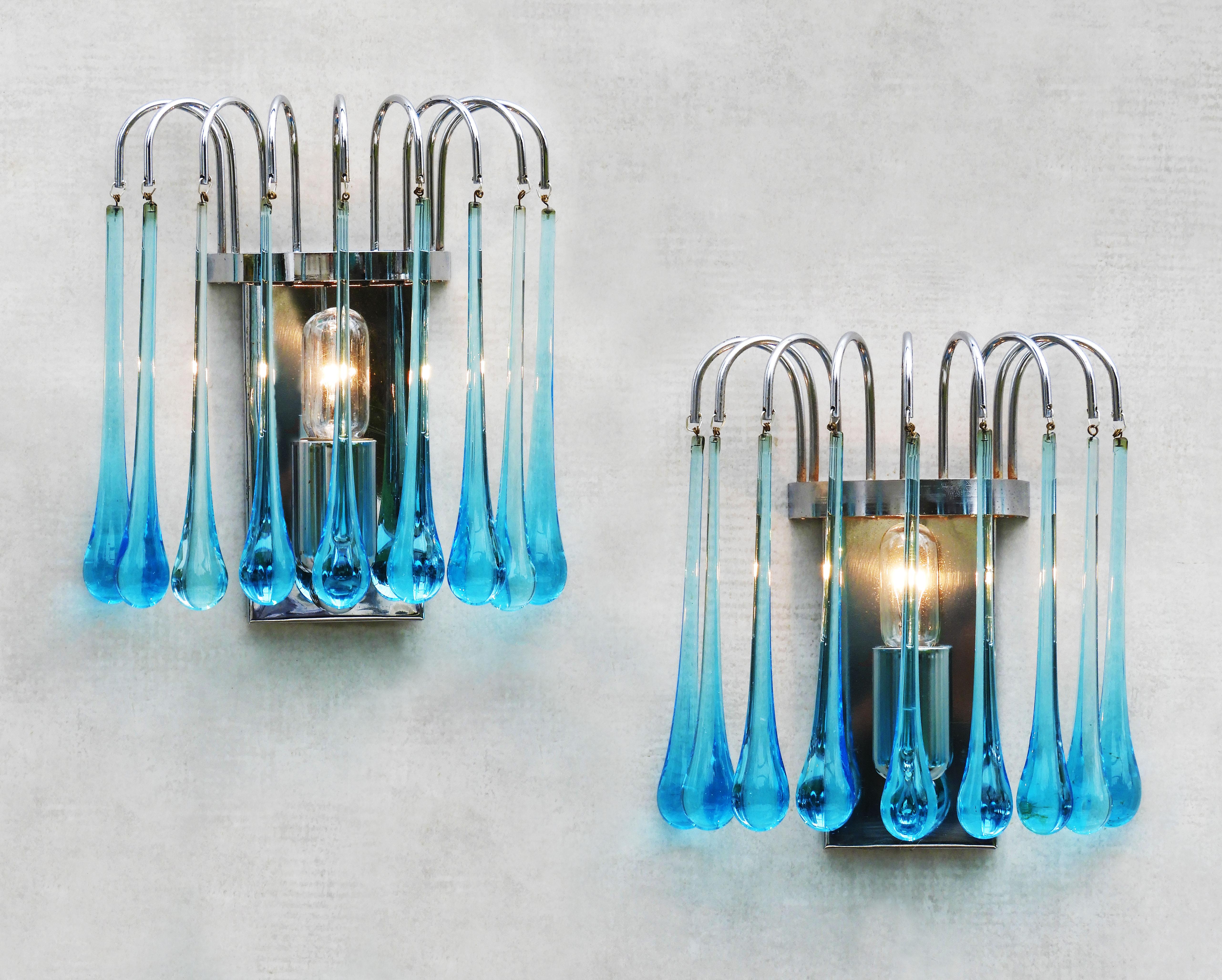 A pair of Paulo Venini-style waterfall wall light sconces.
Striking Murano glass cascades each with nine blue ‘teardrop’ crystals on a chrome frame.   
In great vintage condition with good patina and no losses to glass.  Completely rewired (for your