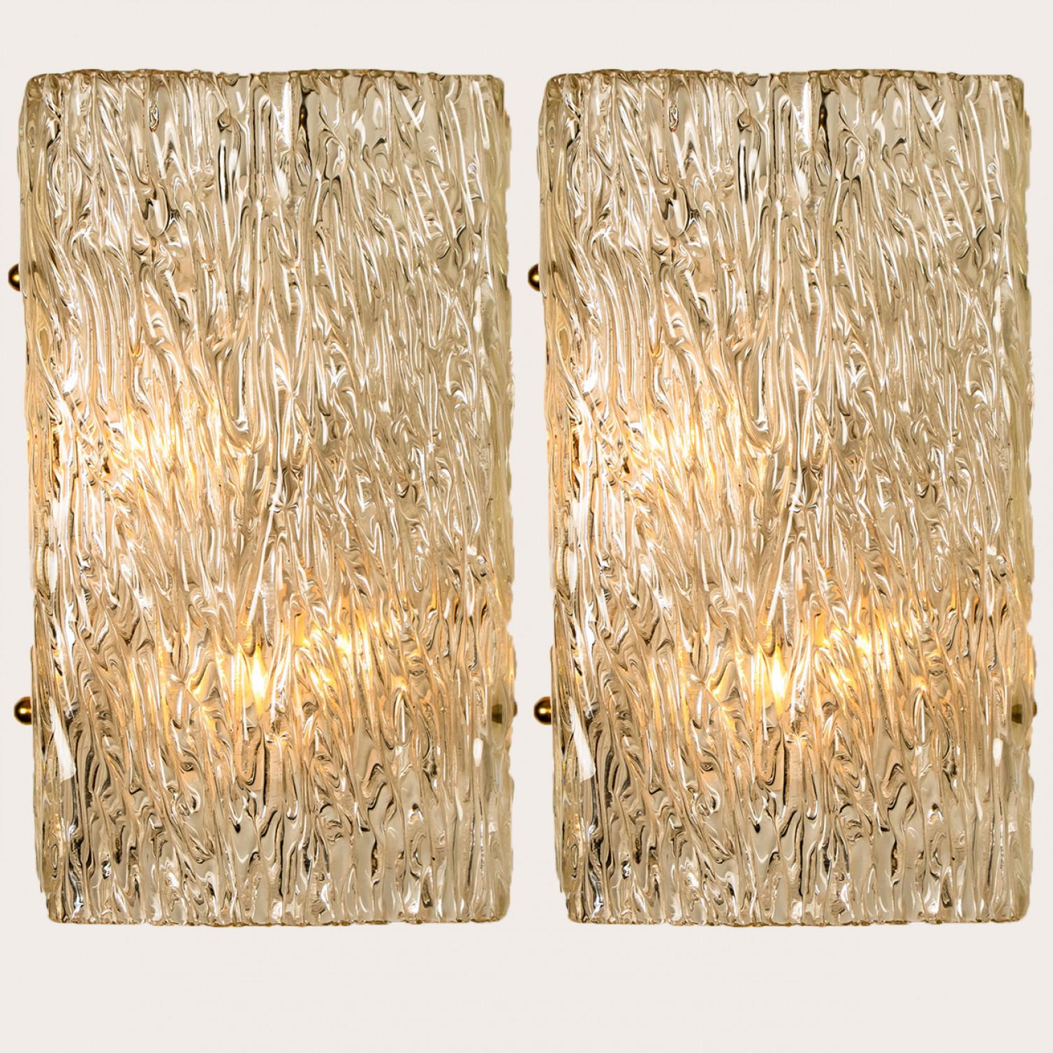 Beautiful high quality light fixture made by Kalmar, Austria. Manufactured in mid century, circa 1970 (at the end of 1960s and beginning of 1970s).

This wall light features lights made of handmade wave textured glass and white back plate. The sides