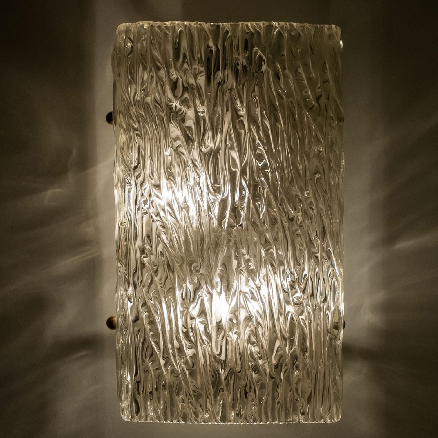 Beautiful high quality light fixture made by Kalmar, Austria. Manufactured in mid century, circa 1970 (at the end of 1960s and beginning of 1970s).

This wall light features lights made of handmade wave textured glass and white back plate. The sides