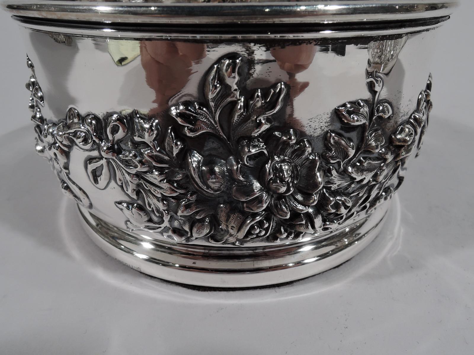 Pair of wedding-gift quality American sterling silver wine bottle coasters, circa 1890. Round with chased garland—bunched ribbon-tied flowers. Three-letter script monogram. Wood bottom. Marked “Sterling” and “925/1000 Fine”. One numbered 4603. Total