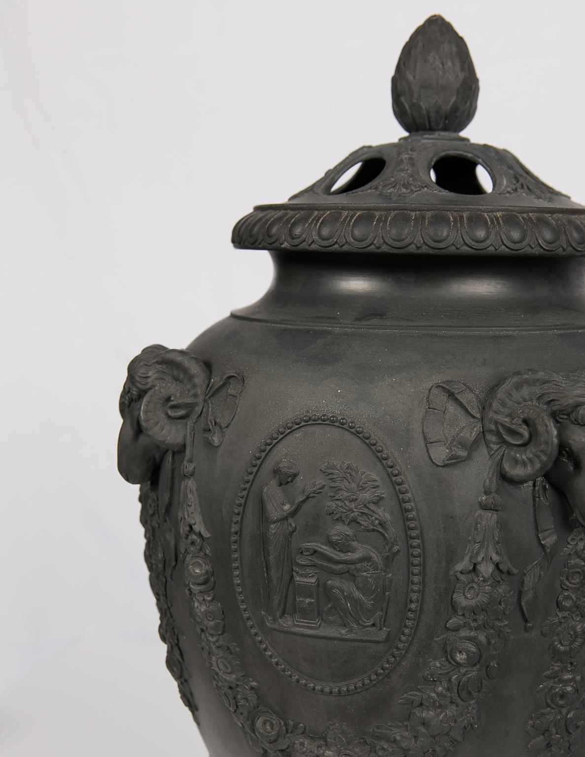 We are pleased to offer this exquisite pair of Wedgwood black basalt covered urns made in the early 19th century. An exact pair can be found in the Dwight and Lucille Beeson Wedgwood Collection at the Birmingham Museum of Art. The urns are decorated