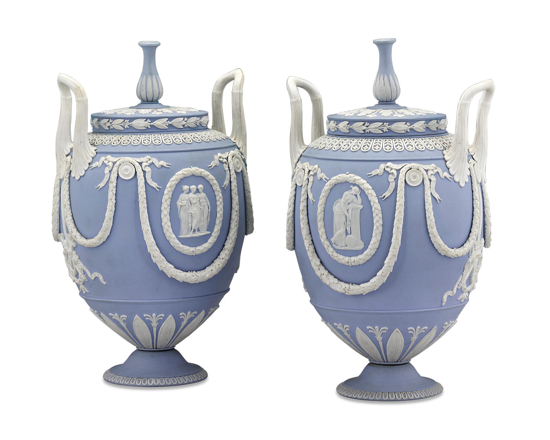 This rare and beautiful pair of urns were crafted by Wedgwood in the firm’s famous pale “Wedgwood blue” jasperware so prized by collectors and connoisseurs alike. Bearing a shape recalling Ancient Greek pottery, neoclassical scenes of maidens