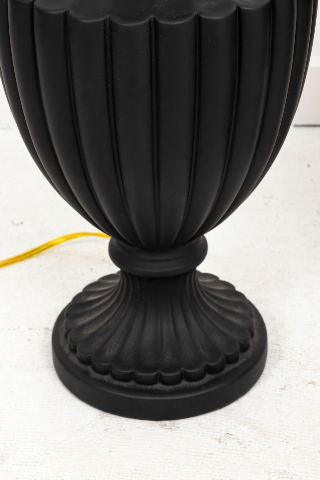 Pair of Wedgwood style black basalt ware urn lamps with reeded detail in ceramic, circa 1980s. Please note of wear consistent with age including minor finish loss. Made in the United States. Shades not included.