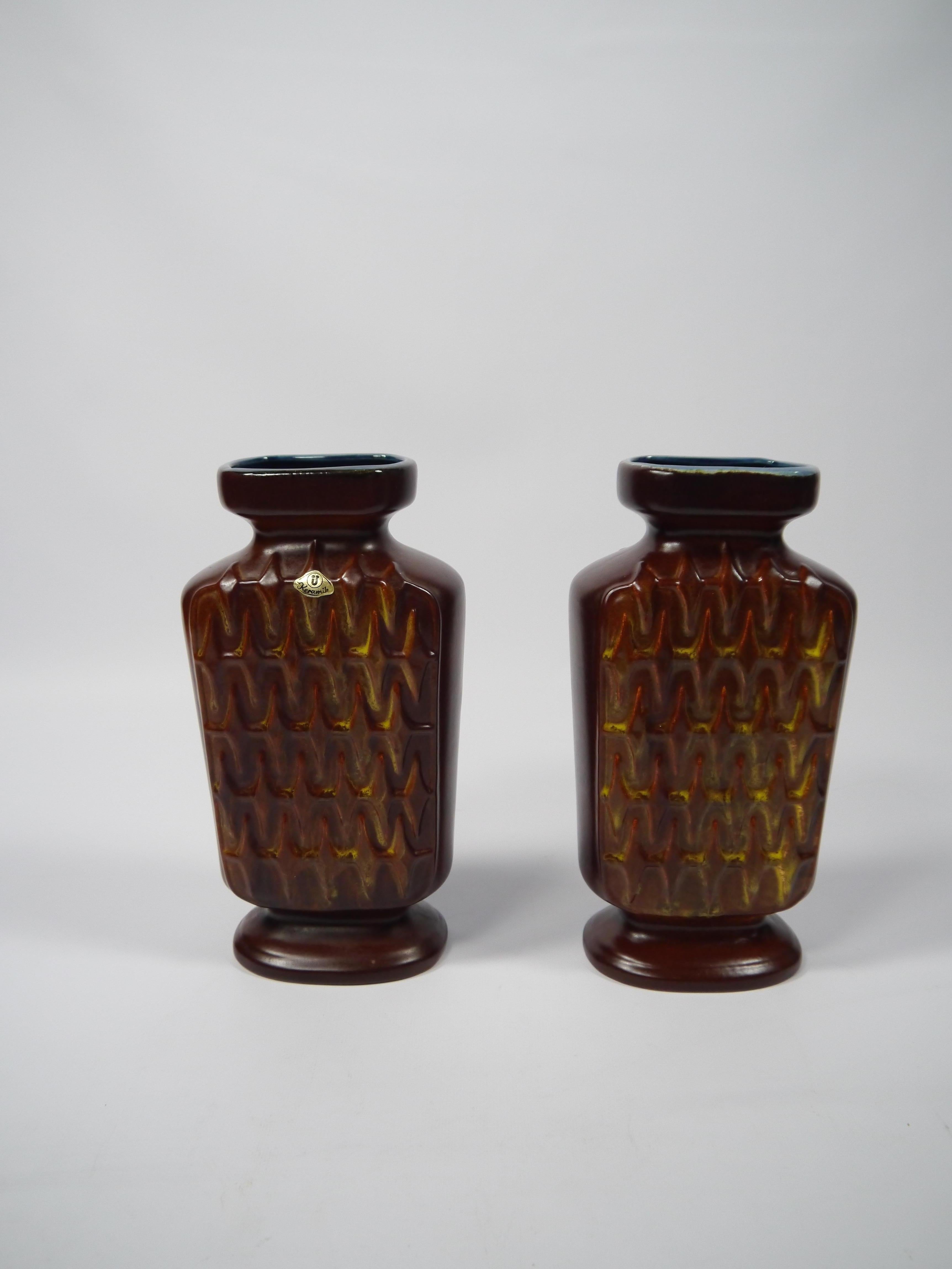 Pair of glazed ceramic vases made by Üebelacker Keramik in West Germany 1950s. Clean and distinct wave pattern, brown-reddish glaze with yellow/red/orange hues reminiscent of flames within the pattern and contrasting blue glaze to top and inside.