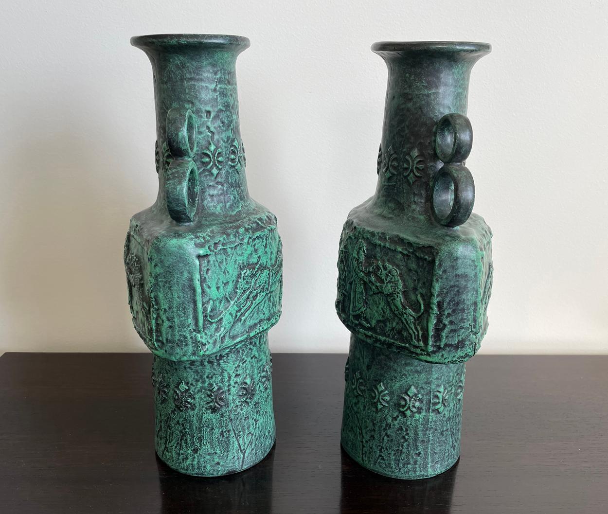 An unusual and highly decorative pair of West German vases in the Grecian style. 

The green tapering bodies with double looped handles above a frieze with scenes of ancient armed warriors. 

The base marked 'W Germany 335-40'.