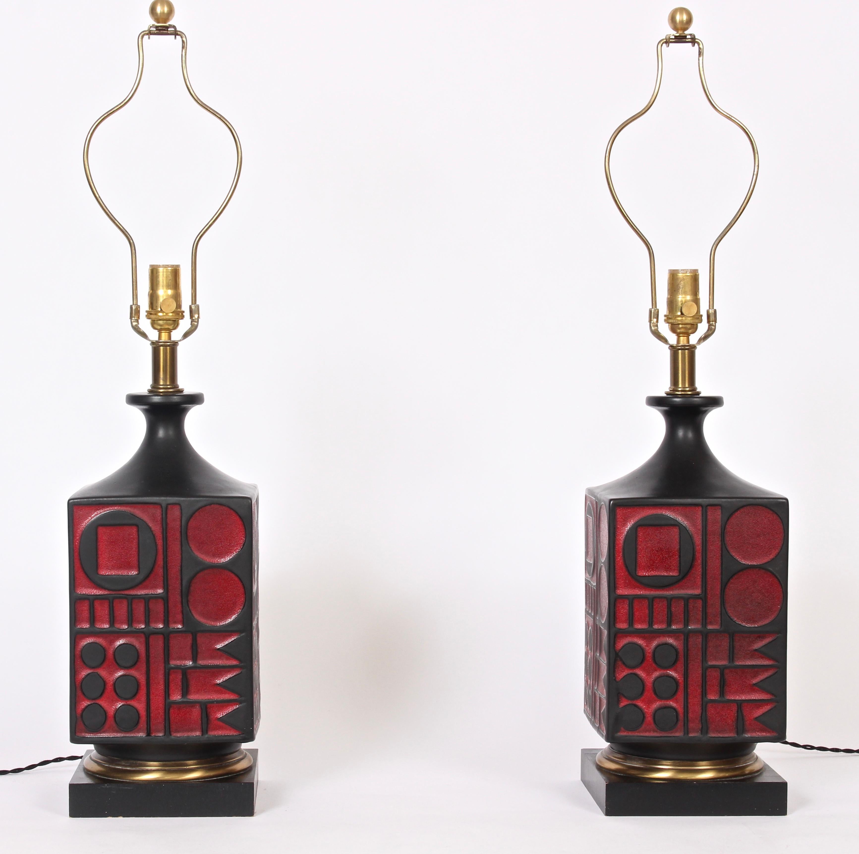 Pair of American midcentury Westwood Industries ceramic table lamps in the style of Tony Paul. Featuring a square black matte glazed smooth textured relief ceramic form with red circle square and flag geometrics on square black enameled wood base