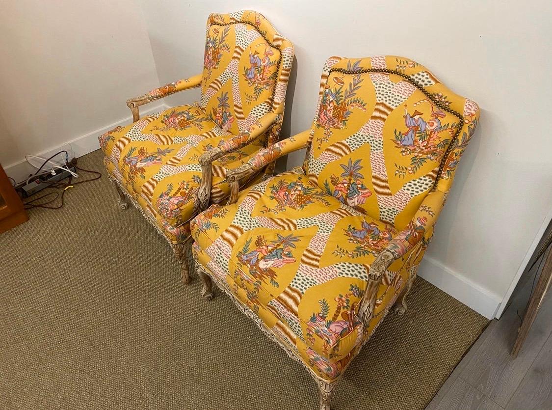 Elegant yet fun whimsical French bergères, a matching pair. And all original except for the fabric which is much more recent and very luxurious, circa 1960s. Features exquisite carvings on the wood base.