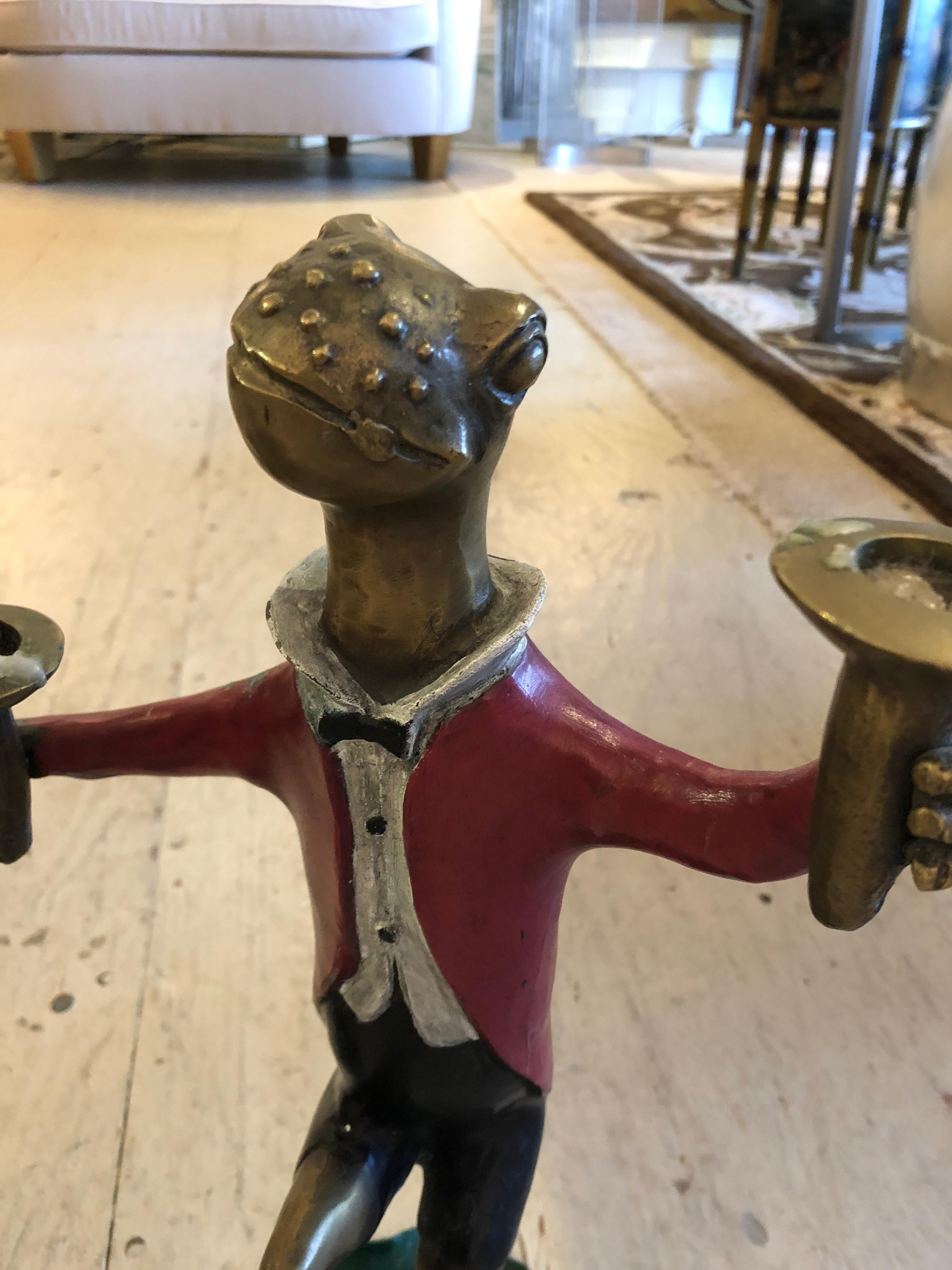 Charming pair of painted bronze candlesticks, one is a dapper Mr. dancing frog in red jacket, and his partner is a tutu'd frogette, equally jovial.