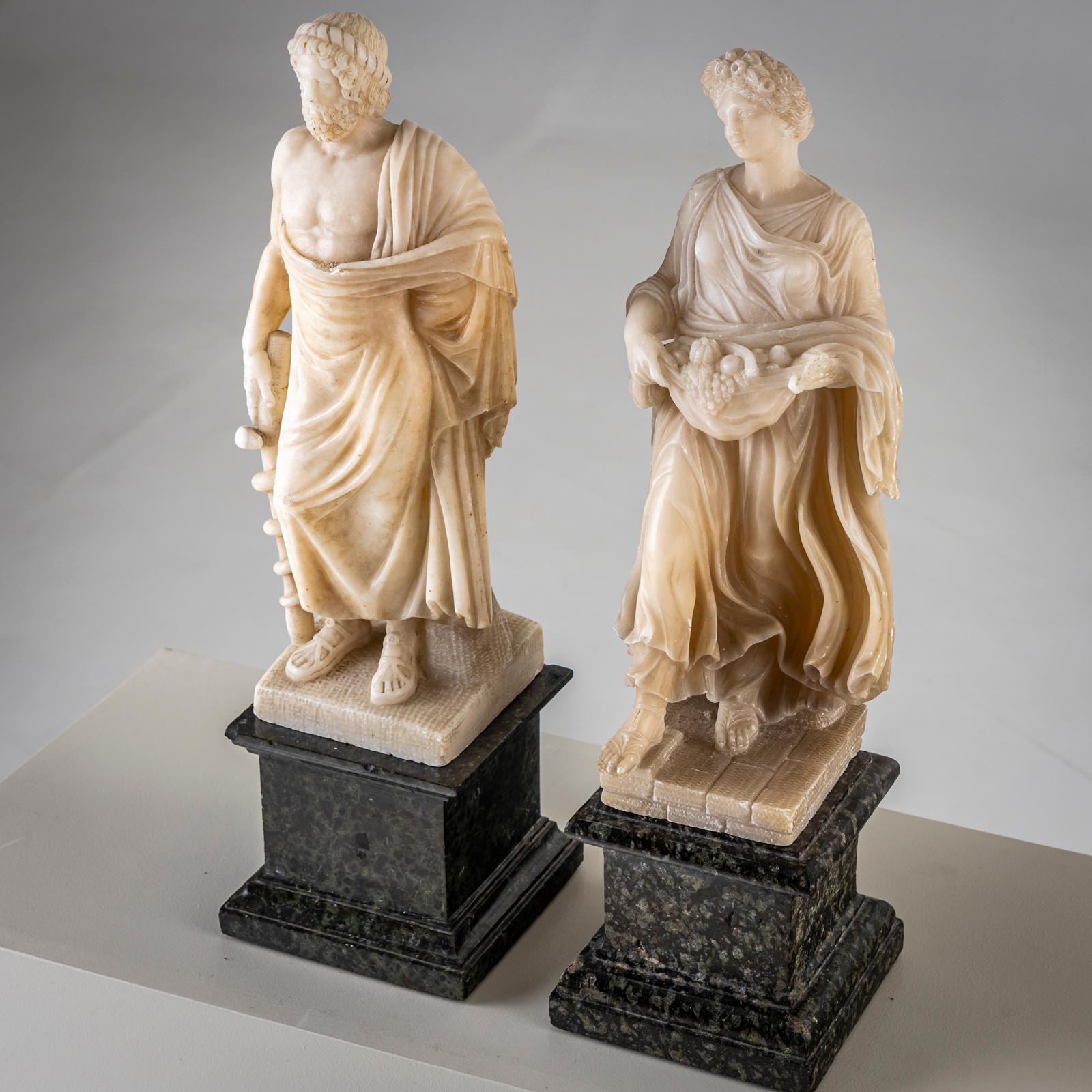 Coppia di sculture in alabastro bianco su una base di marmo verde. Una femmina, l'altra maschio.

Scultura femminile: 47 x 14,5 x 13,5 cm
Scultura maschile: 47 x 13,5 x 13,5 cm
Piedistallo: 13,5 x 13,5 cm