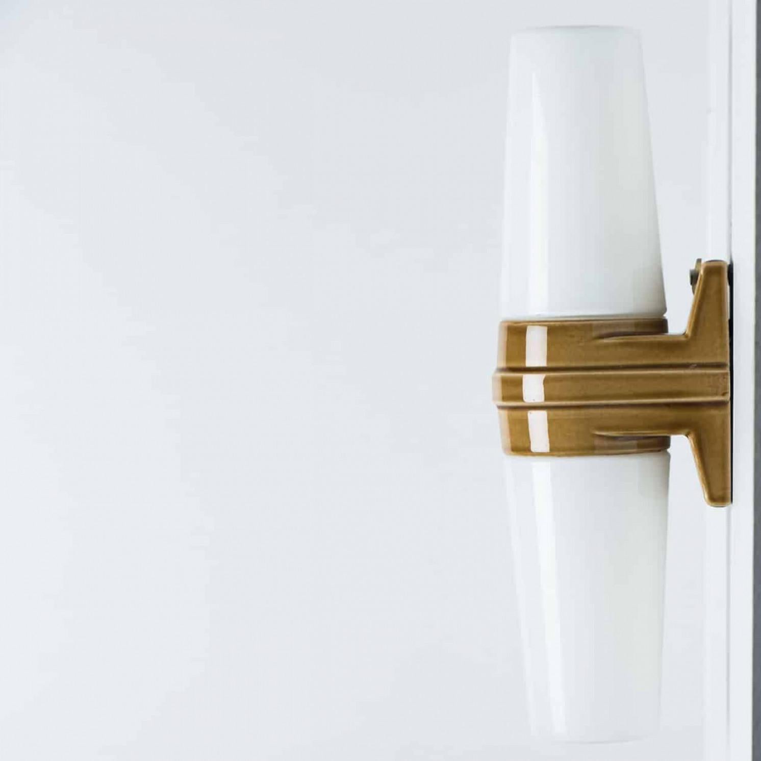 Superbes appliques murales, fabriquées en Suède dans les années 70. Les lampes sont composées de deux coupes de verre blanches en forme de cône, maintenues ensemble par une bande de céramique brune au milieu, créant un effet de classe et de