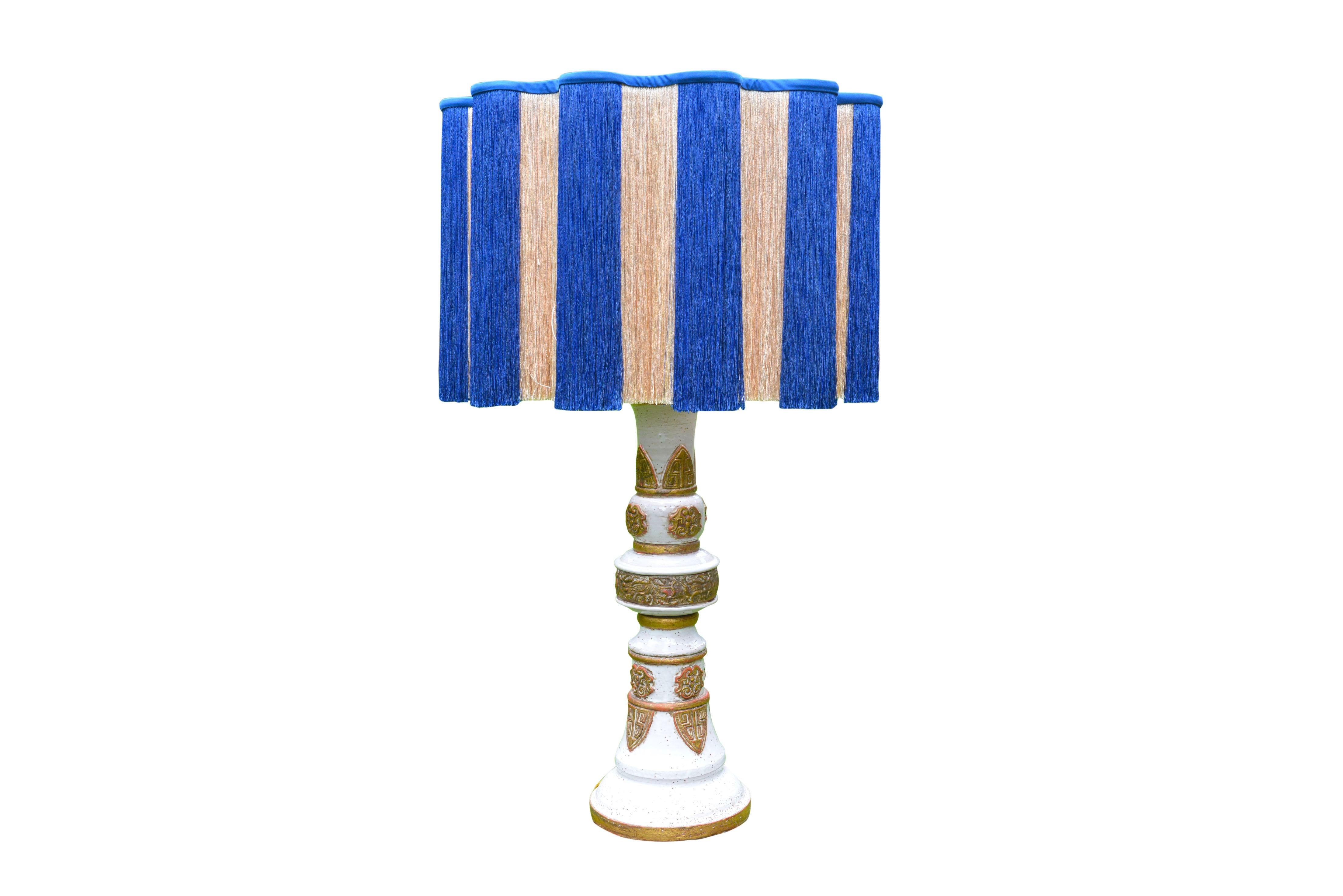 Stunning pair of table lamps in white and gold chinoiserie inspired ceramic, made in France around 1960. With exquisite bespoke cream and blue fringe serpentine lamp shades.