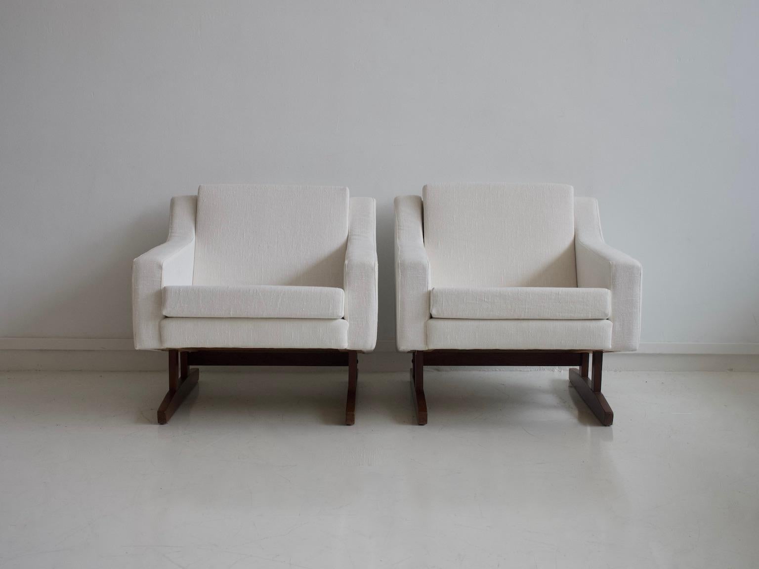 Pair of armchairs from the 1960s, loose seat and back cushions upholstered in white fabric. Legs, that resemble ice skates, are made of teak. Good vintage condition, some tiny marks on upholstery.