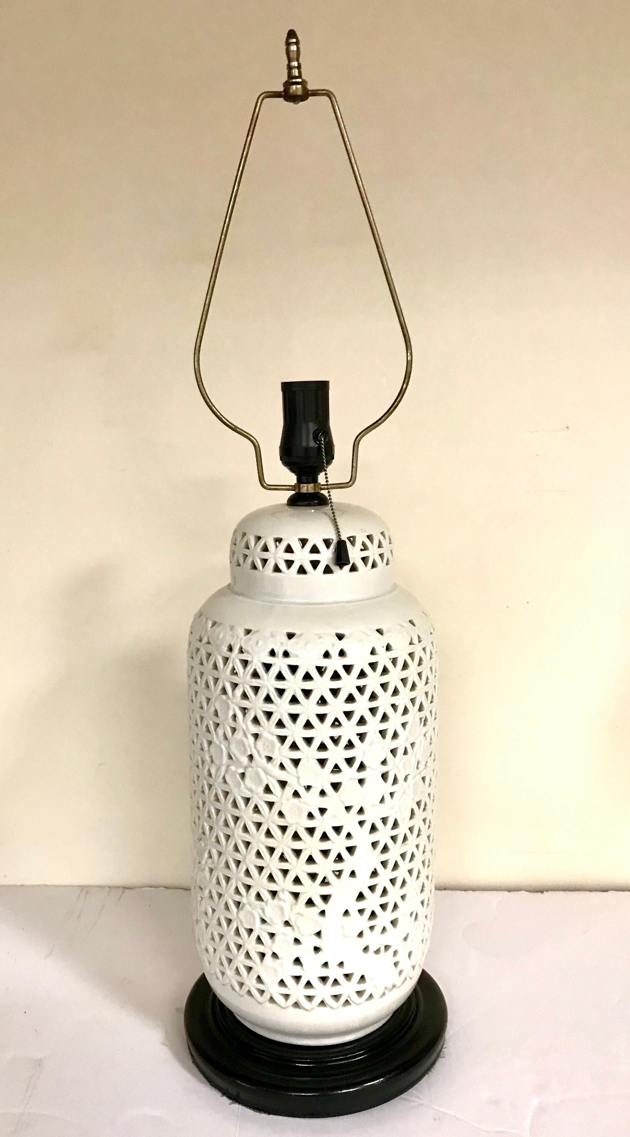 Beautiful, intricate and delicate. These Blanc de Chine lamps are neutral enough for any room but will definitely make an impact wherever used. Their porcelain bodies are reticulated with a cherry tree motif. They rest on ebonized wood bases. Silk