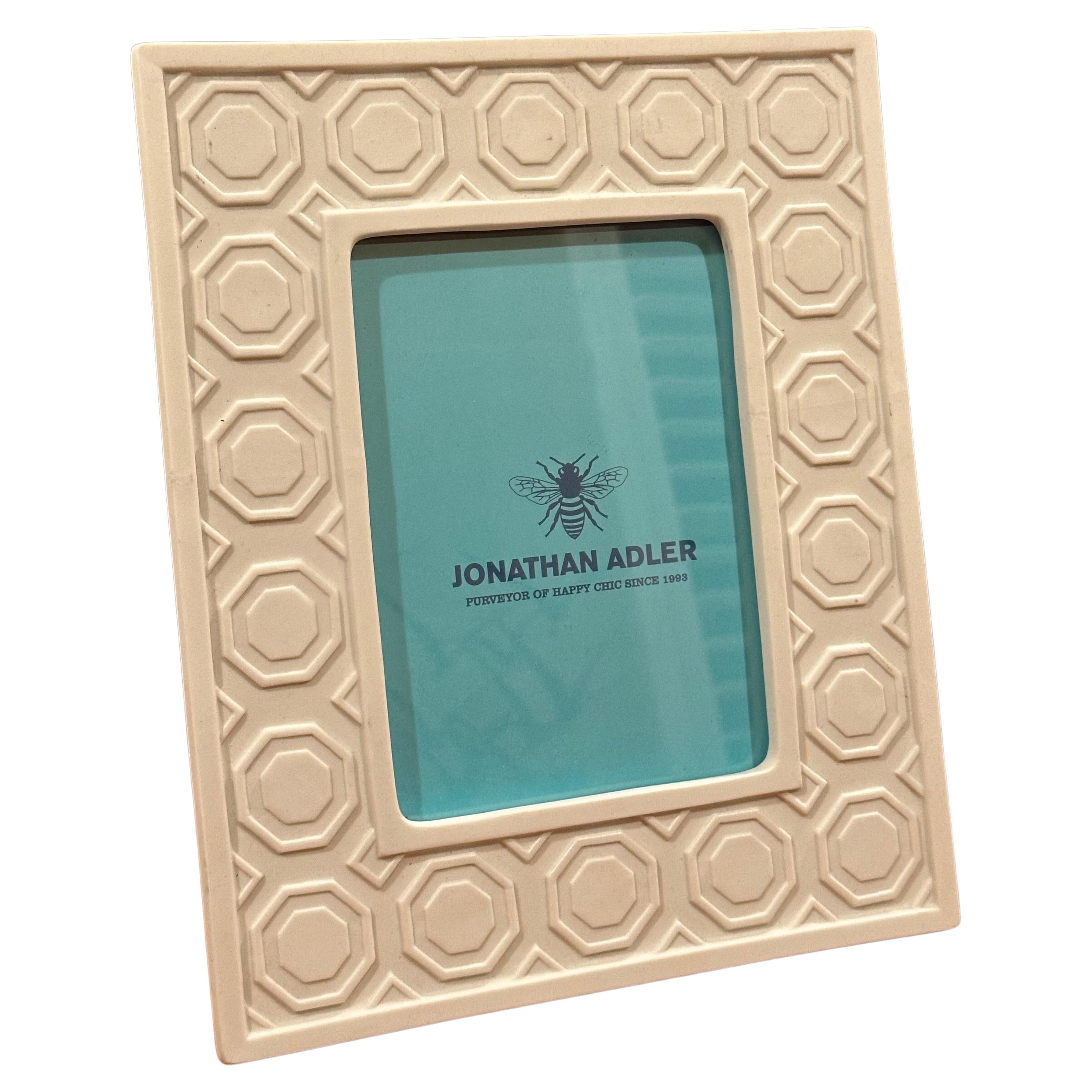 A pair of white ceramic picture frames by Jonathan Adler, circa 2000s.  The larger frame holds a 5x7 photograph and measures 9.5