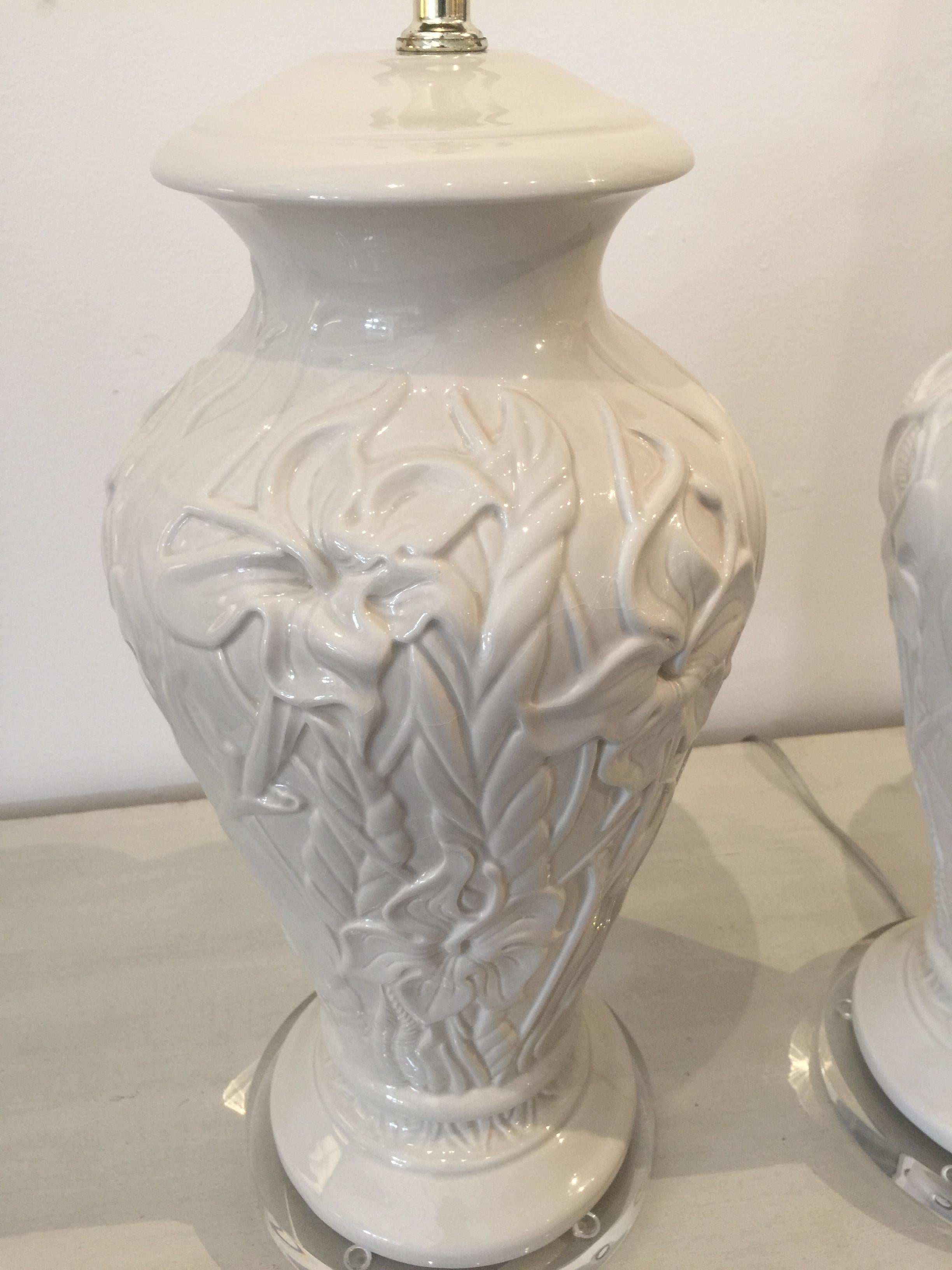 Pair of white table lamps with raised floral pattern of lilies.
The lamps have been rewired and are UL listed.
Not recommended to use more than 150 watts.
The Lucite bases are clear and smooth.

Measures: Height 24