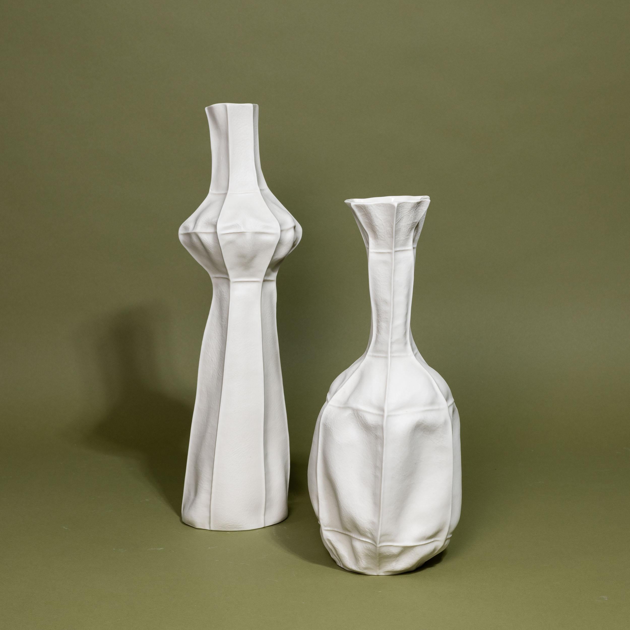 A pair of white porcelain vases made by casting into leather molds. 

As a result of the production process each item is one-of-a-kind. Set includes one tall vase and one medium vase. 

The vases are watertight.

Tall Vase: 5.5