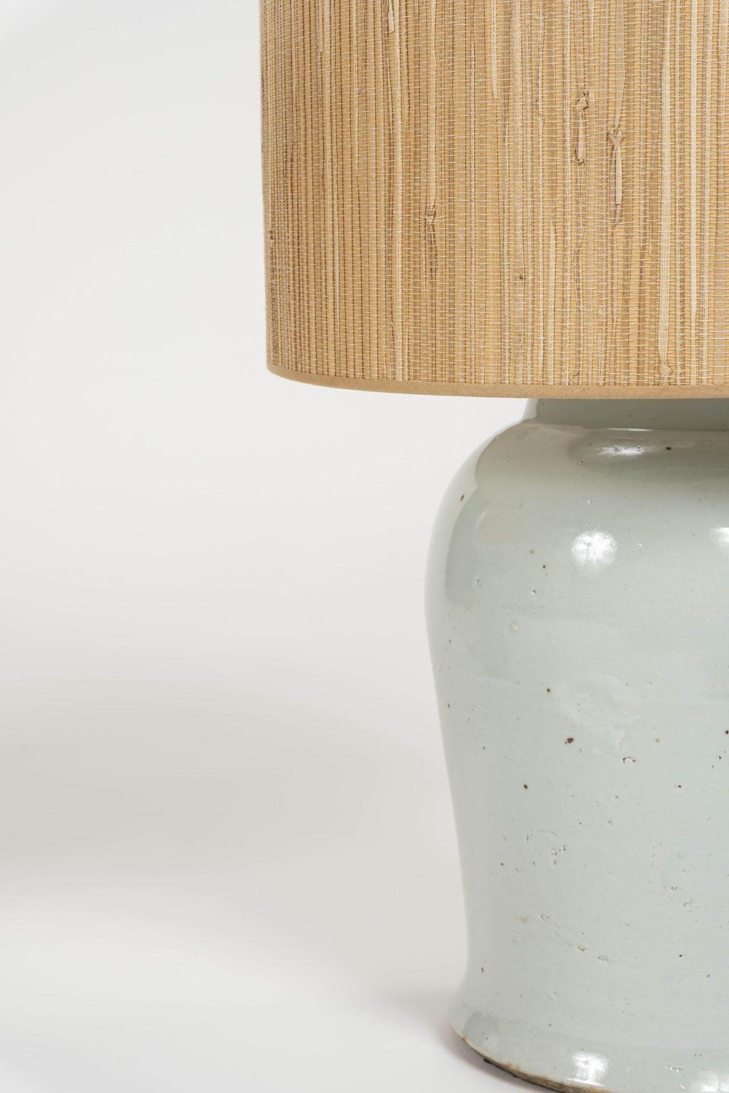 Pair of vintage white faience jars, newly wired as custom table lamps. Pair includes grass cloth drum shades with rolled edges. Sold together and priced $4,400 for the pair.