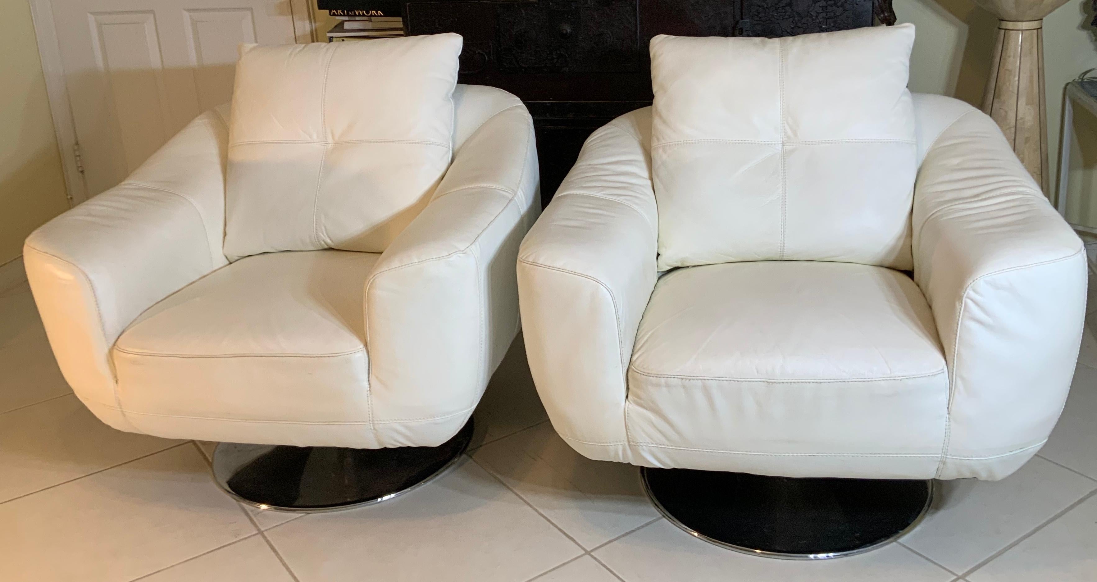 Two vintage modern swivel chairs featuring white faux leather upholstery and round chrome base. Great comfortable to sit and turn, stylish swivel seating adds Mid-Century Modern flare to any interior.

 