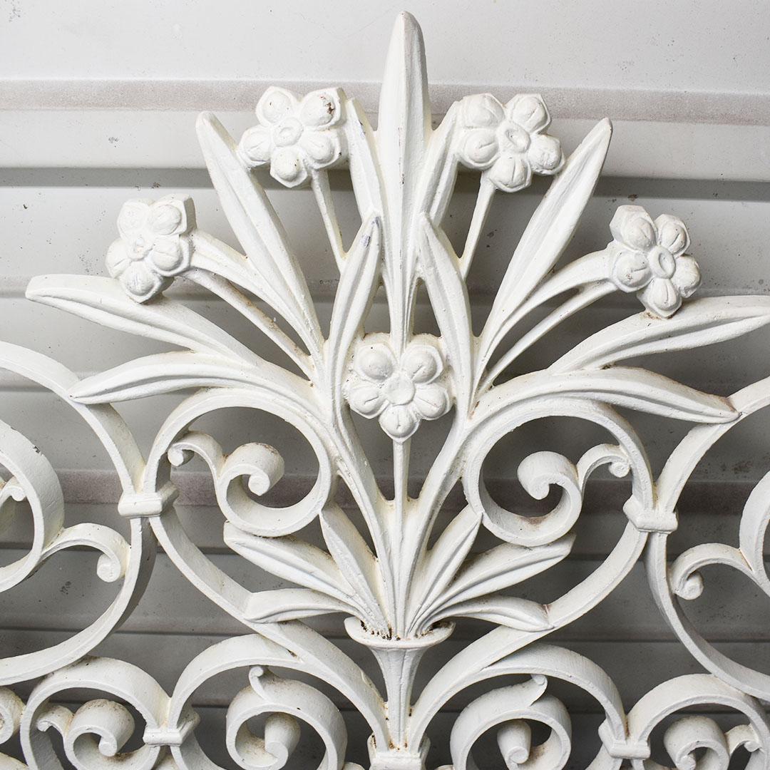 Pair of two Trompe L’Oeil iron headboards. Painted in white, each headboard is created from iron or steel and features a floral motif with vines and Trompe L’Oeil flowers which curl up into a pyramid shape. At the top middle, a bouquet of flowers