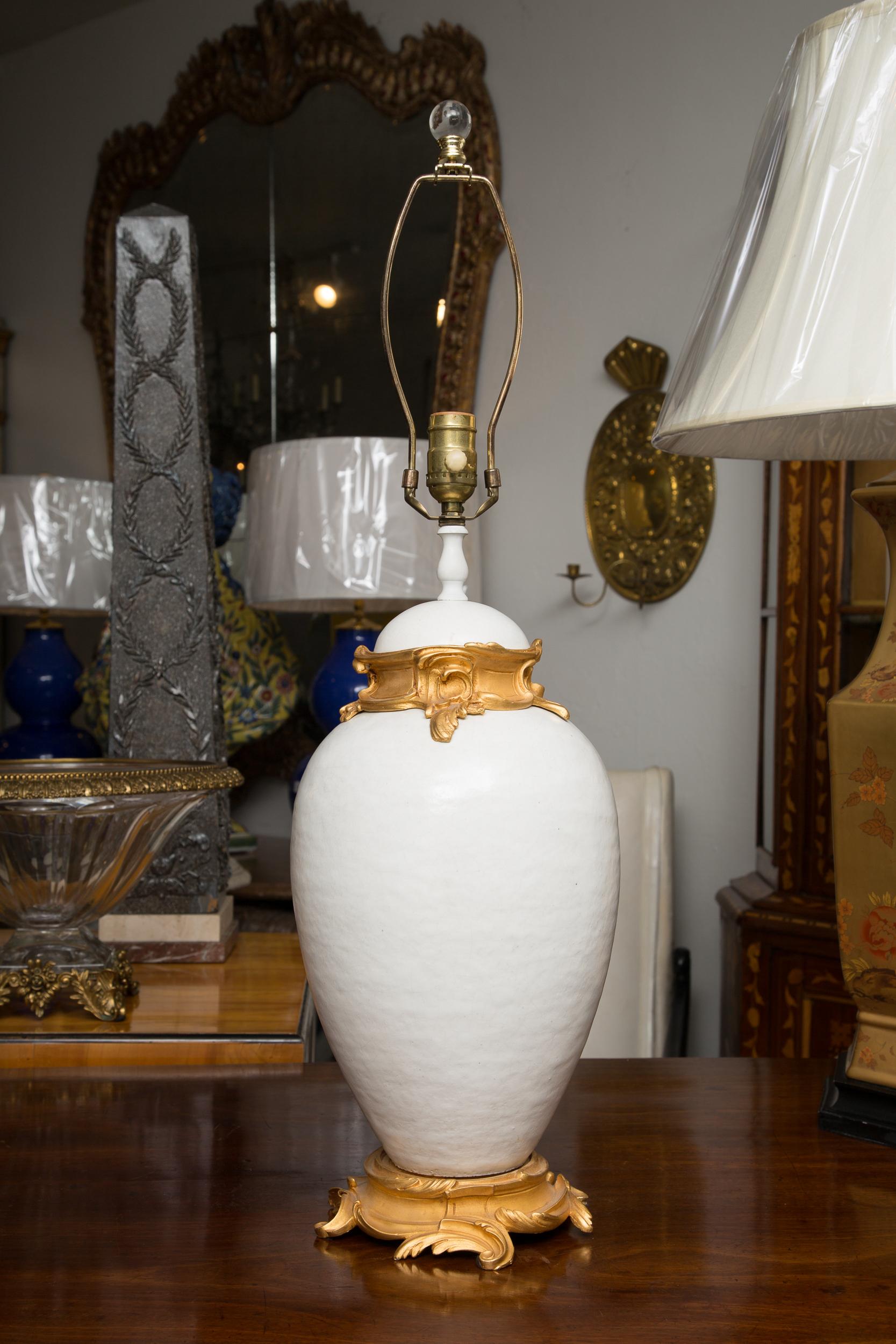 This is a sophisticated pair of white glazed ceramic lamps with gilt bronze mounts, creating a marriage of casual and formal.