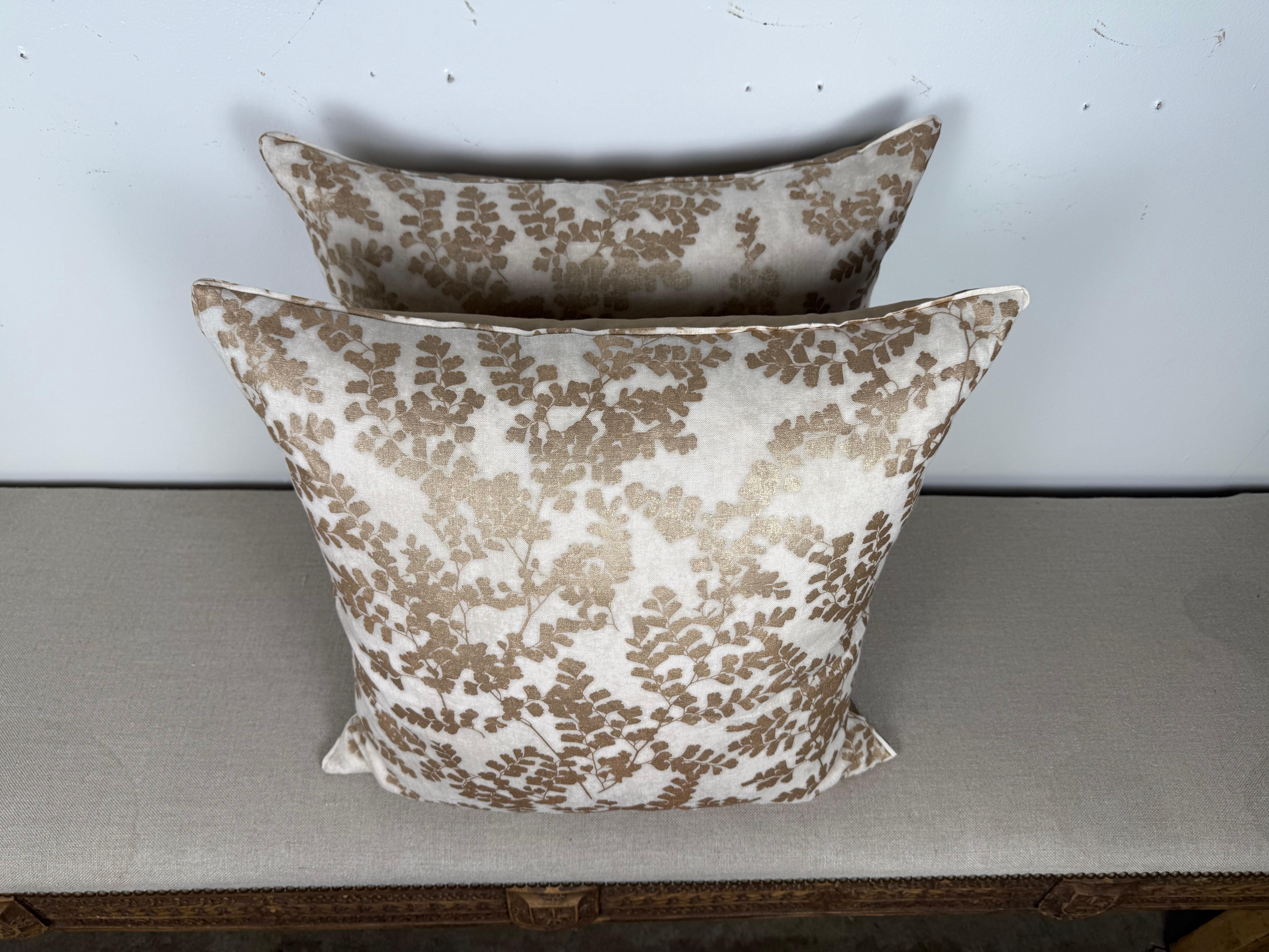 Questa elegante coppia di cuscini di MLA dona una naturale raffinatezza a qualsiasi spazio grazie al delicato disegno botanico bianco e oro. Il fronte presenta un morbido sfondo avorio sovrapposto a un motivo di felci dorate e scintillanti, creando