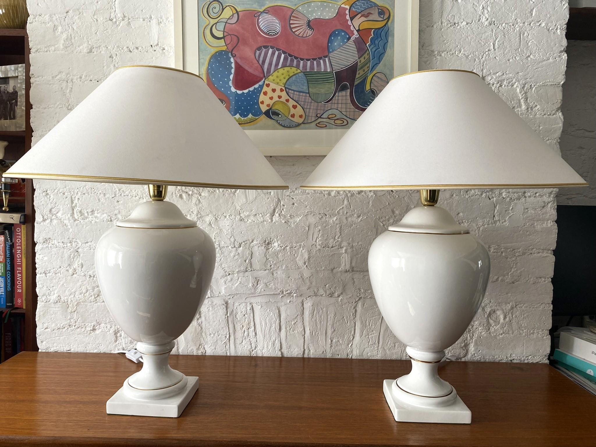 Pair of White & Gold Ceramic Table Lamps & Shades by Stefano Cevoli, Italian, 1980s

Vintage pair of white ceramic table lamps with gold accents, including shades that have a gold simple braid around the top and bottom rim of shade. Designed by