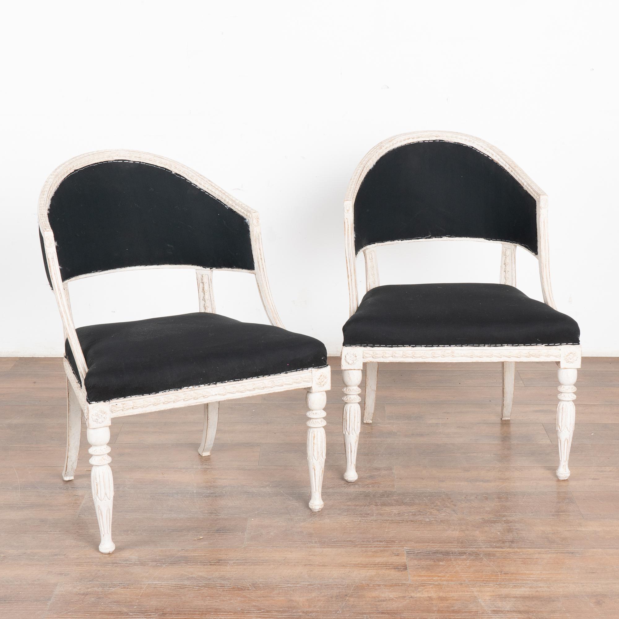Pair, Swedish Gustavian armchairs with a gently curved barrel back and saber back legs, adding to the graceful appeal of each.
Fluted turned front legs and decorative carving embellish the skirt, arms and legs. 
The newer, professionally applied