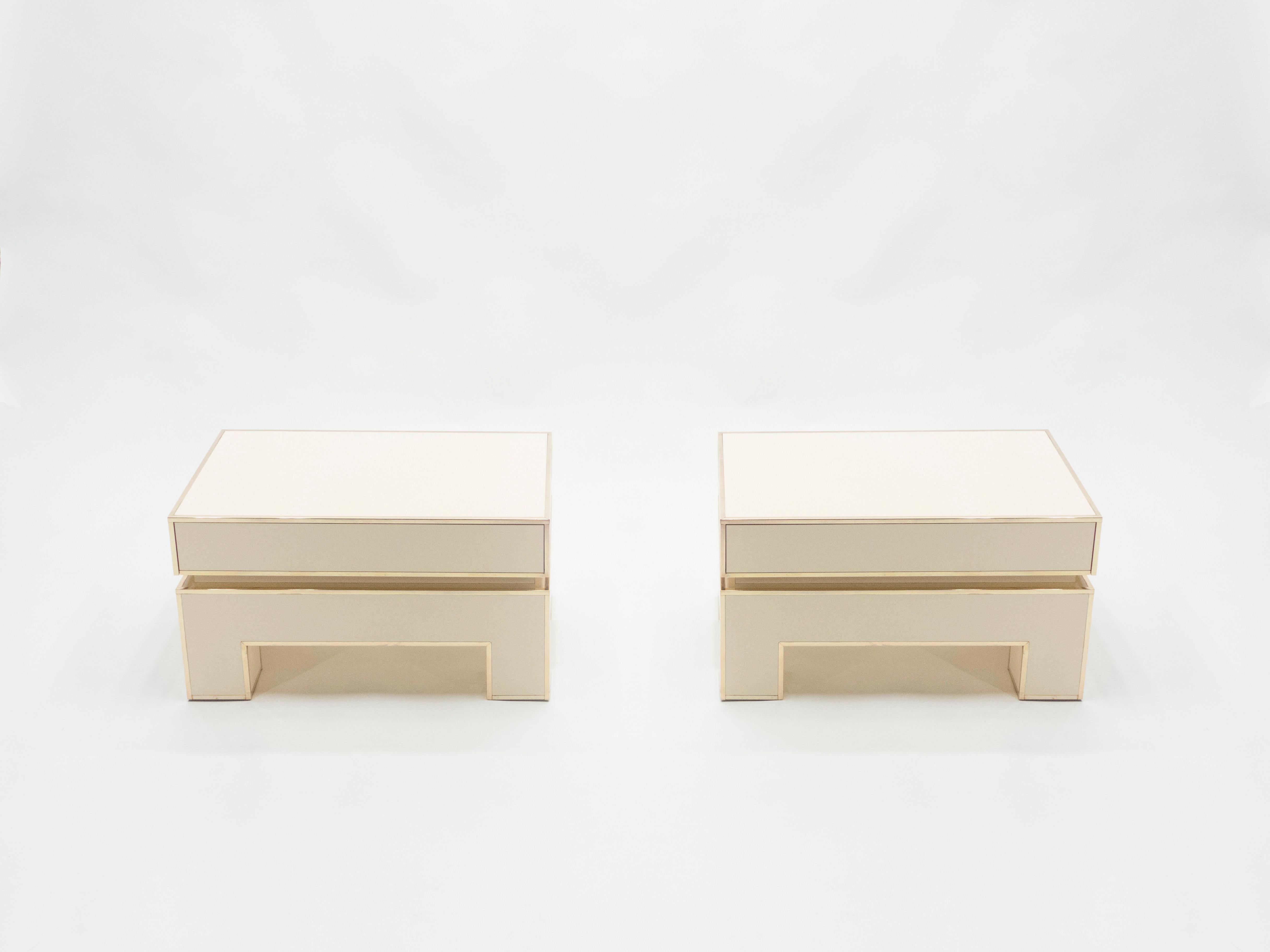 Crispy white lacquer, paired with bright brass accents, feels crisp and luxe on this pair of end tables or low nightstands. Signed by Alain Delon and edited by Maison Jansen in 1975. Their boxy, simple style is typical of both the 1970s and Maison