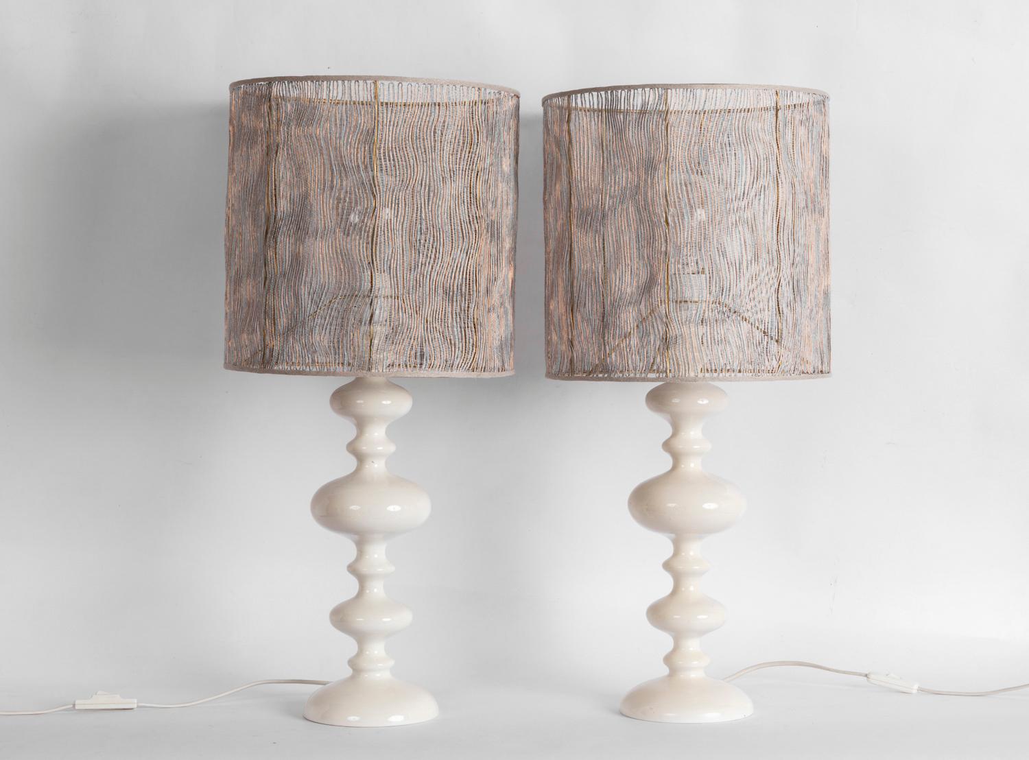 Pair of lamps in turned white lacquered wood with a shaft composed of six flattened different sizes balls, standing on a circular base, slightly bulging.

Cylindrical lampshade with a structure in cotton, linen, copper and nylon, drawing vertical