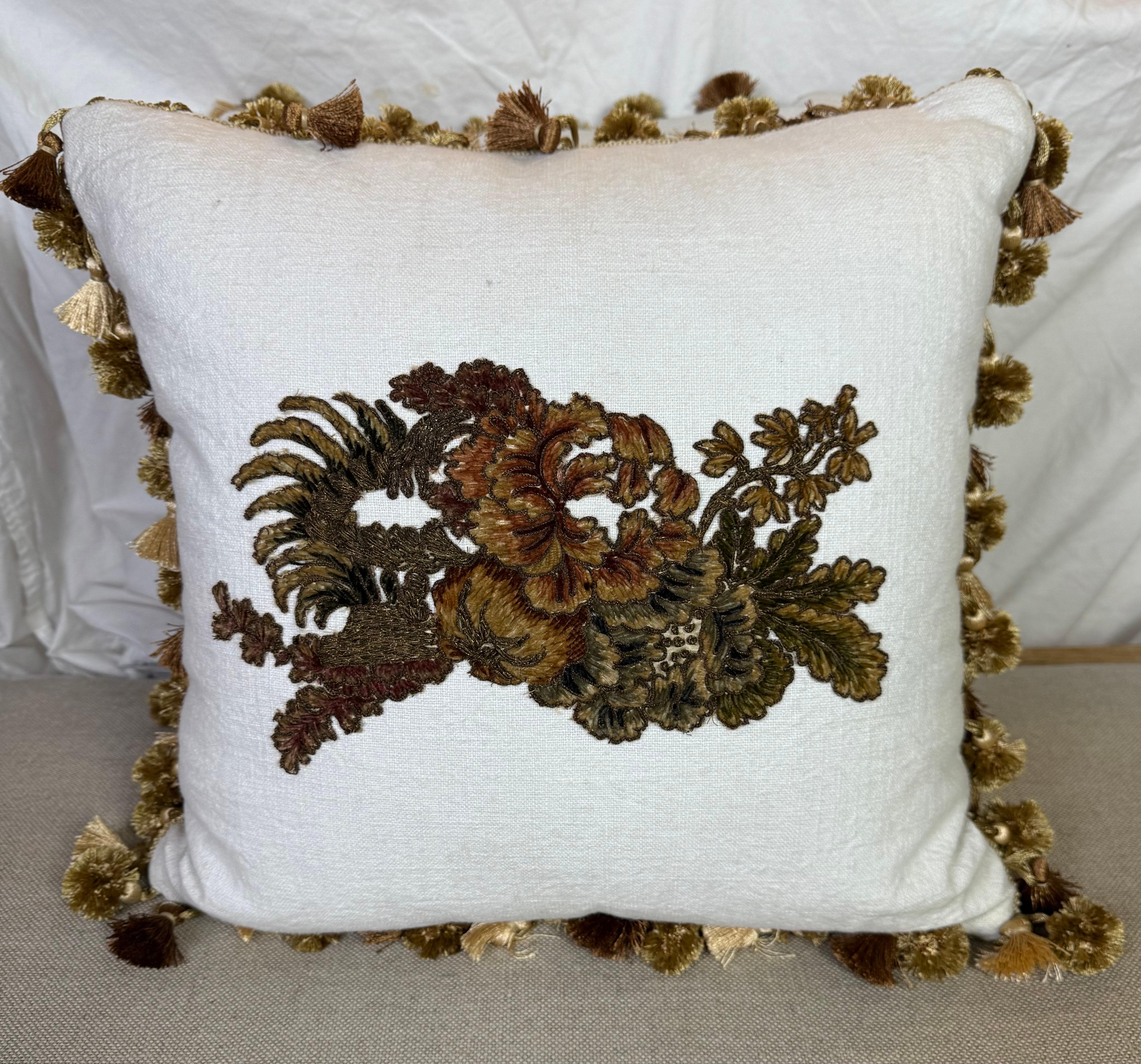 Questi eleganti cuscini in lino bianco sono caratterizzati da un'intricata applicazione francese del XIX secolo in ciniglia metallica e ricamata, che mostra un ricco motivo floreale nei toni del marrone, dell'oro e del verde. Il ricamo aggiunge una