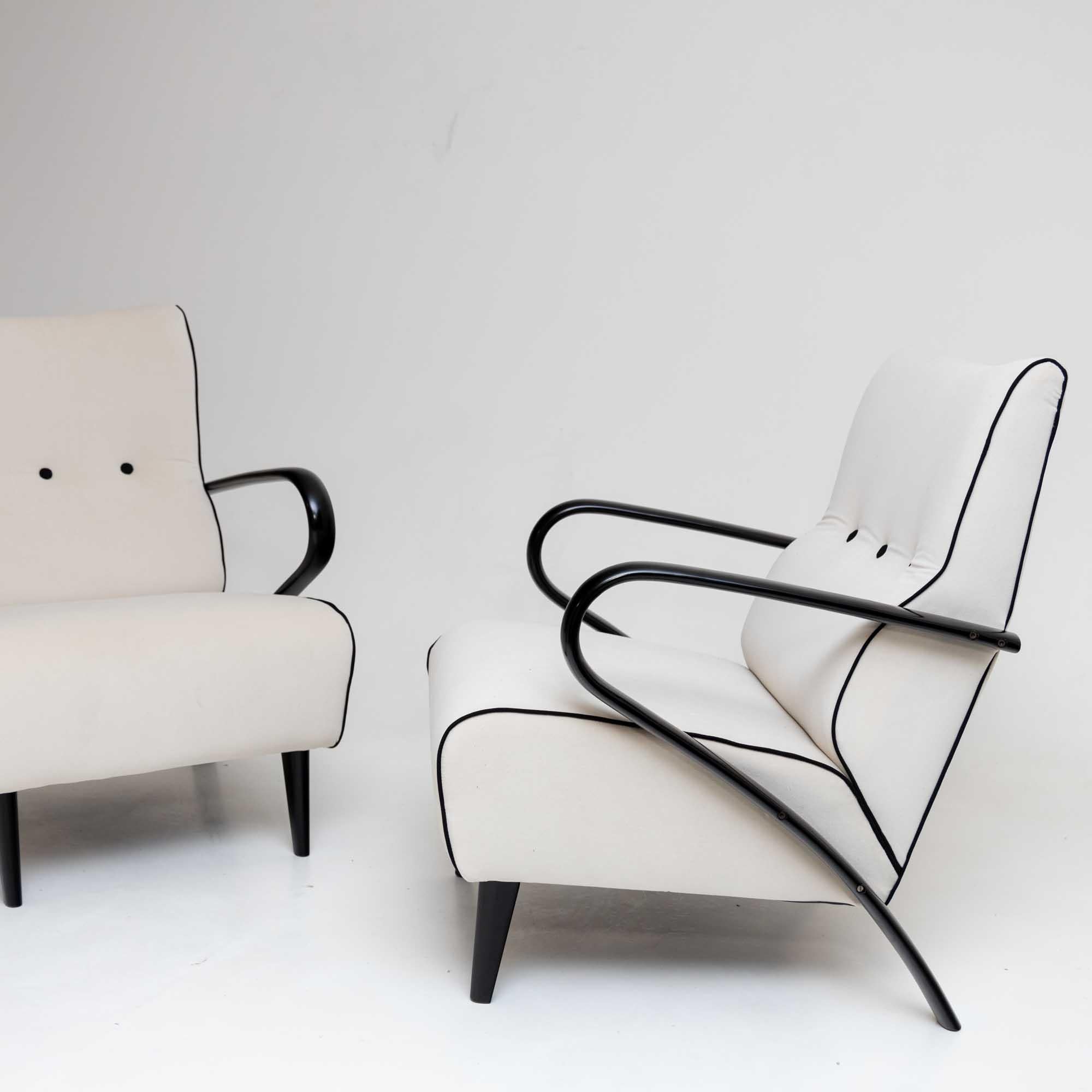 Ein Paar elegante Loungesessel mit ebonisierten Armlehnen und gepolsterten Sitzen. Die Sessel sind poliert und neu gepolstert worden. Der weiße Stoff wird durch schwarze Knöpfe und schwarze Paspeln auf minimalistische Weise kontrastiert.