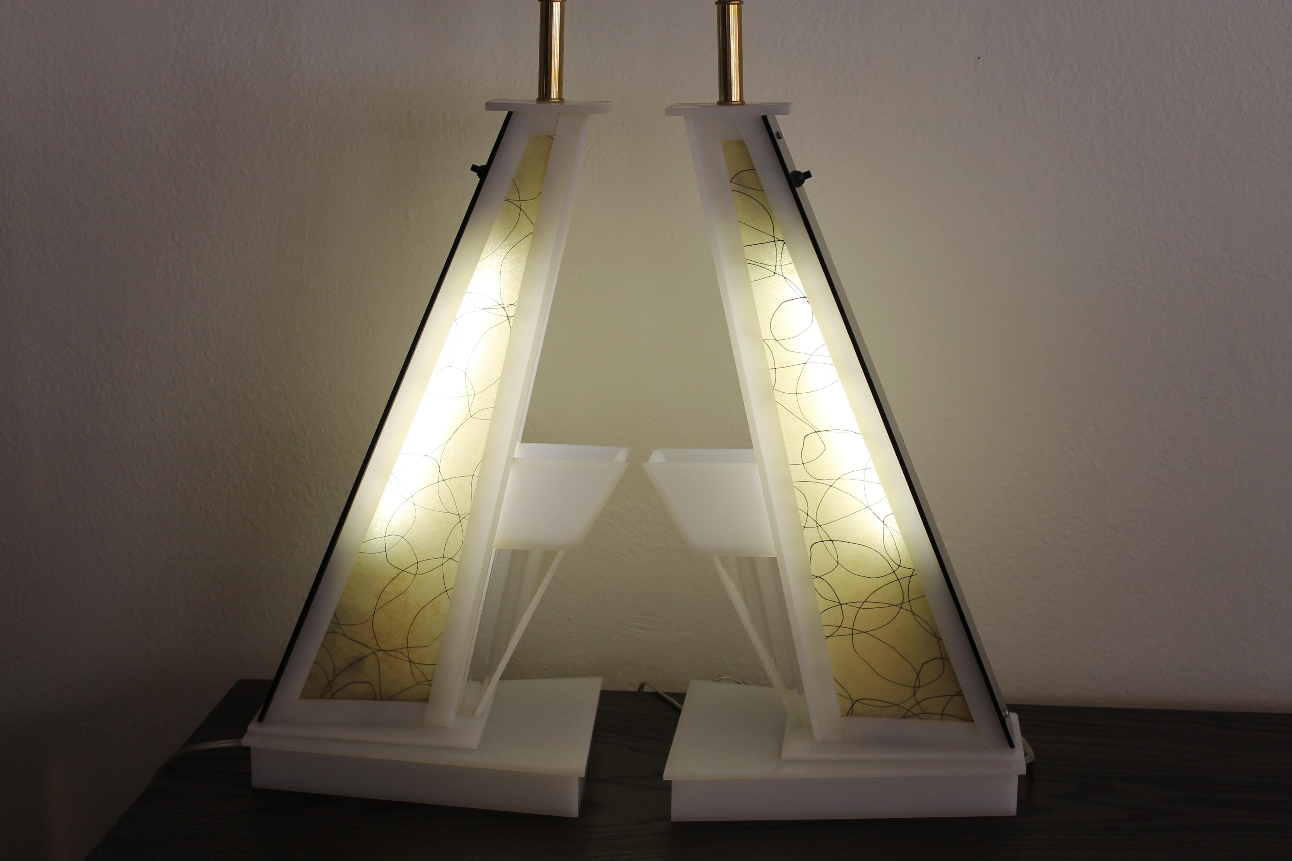 Pair of angular lucite table lamps by the Moss lighting company. Lamps have a switch which lights up the inside portions in addition to the switch on the sockets.  Lamps measure 9