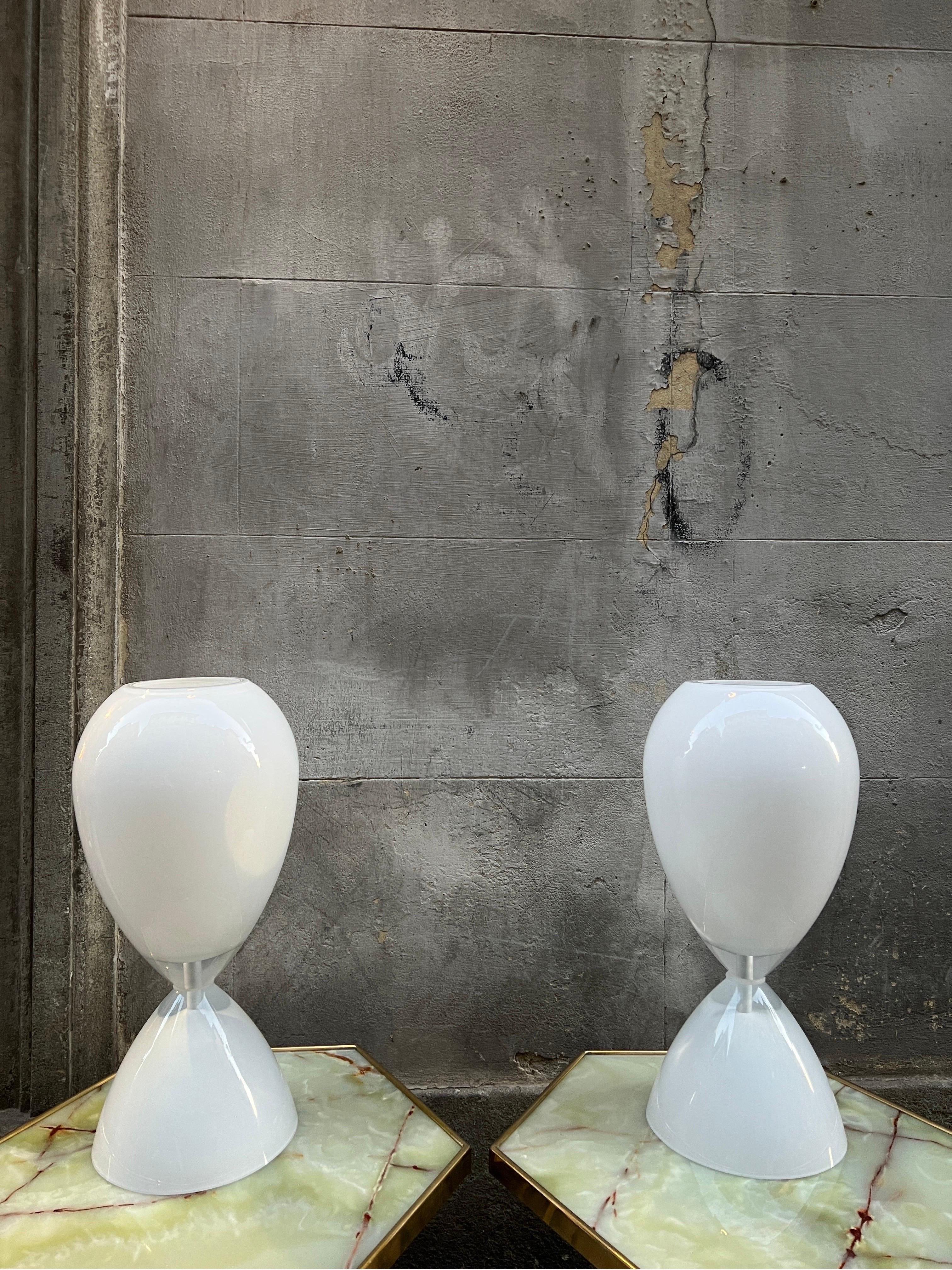Pair of white hourglass shaped Murano Glass table lamps. 
Italian Vintage design mid-century era.
One bulb each lamp.
Available a blue version.
