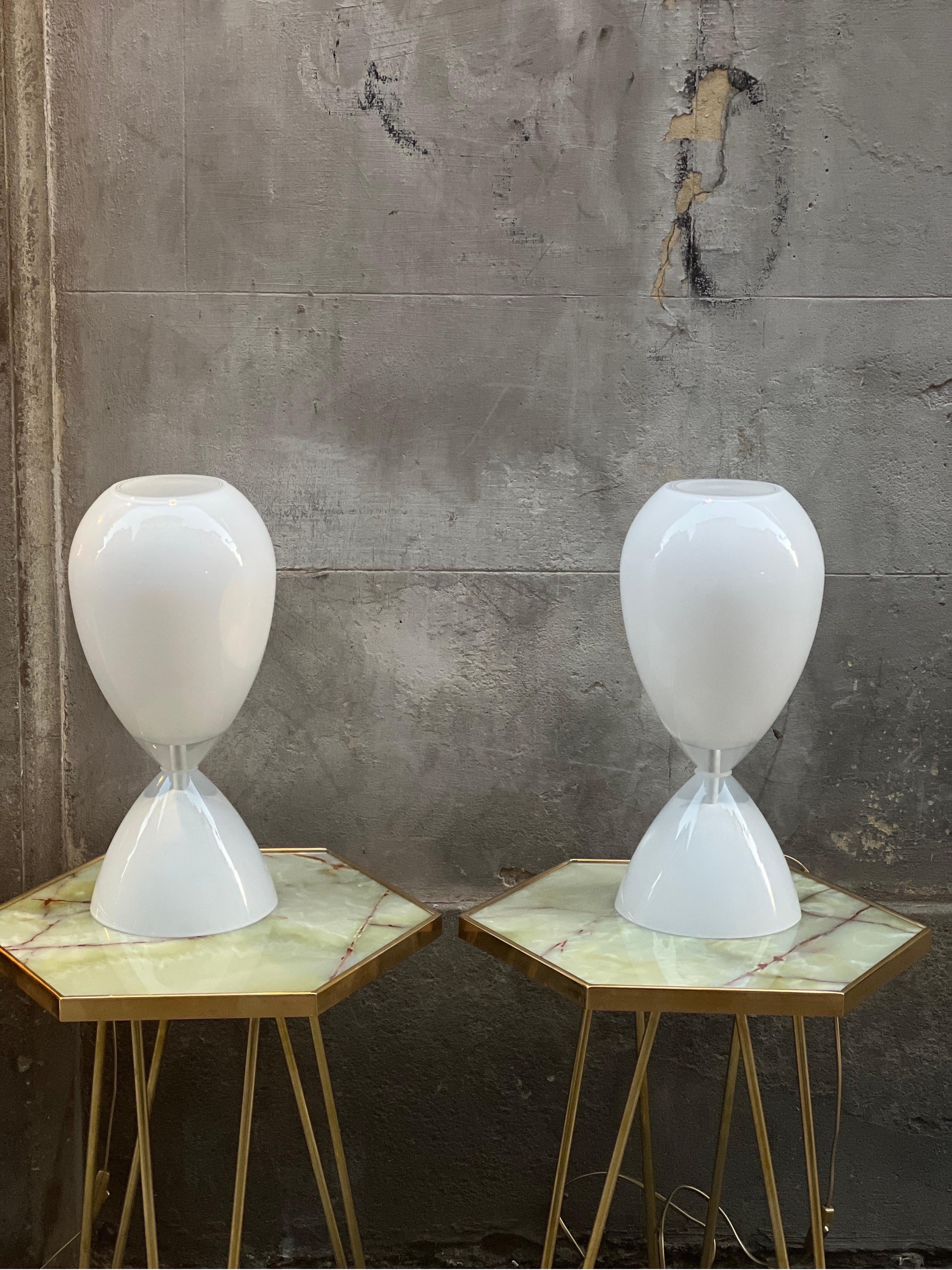 Pair of white hourglass shaped Murano Glass table lamps. 
Italian Vintage design midcentury era.
One bulb each lamp.
Available a blue version.