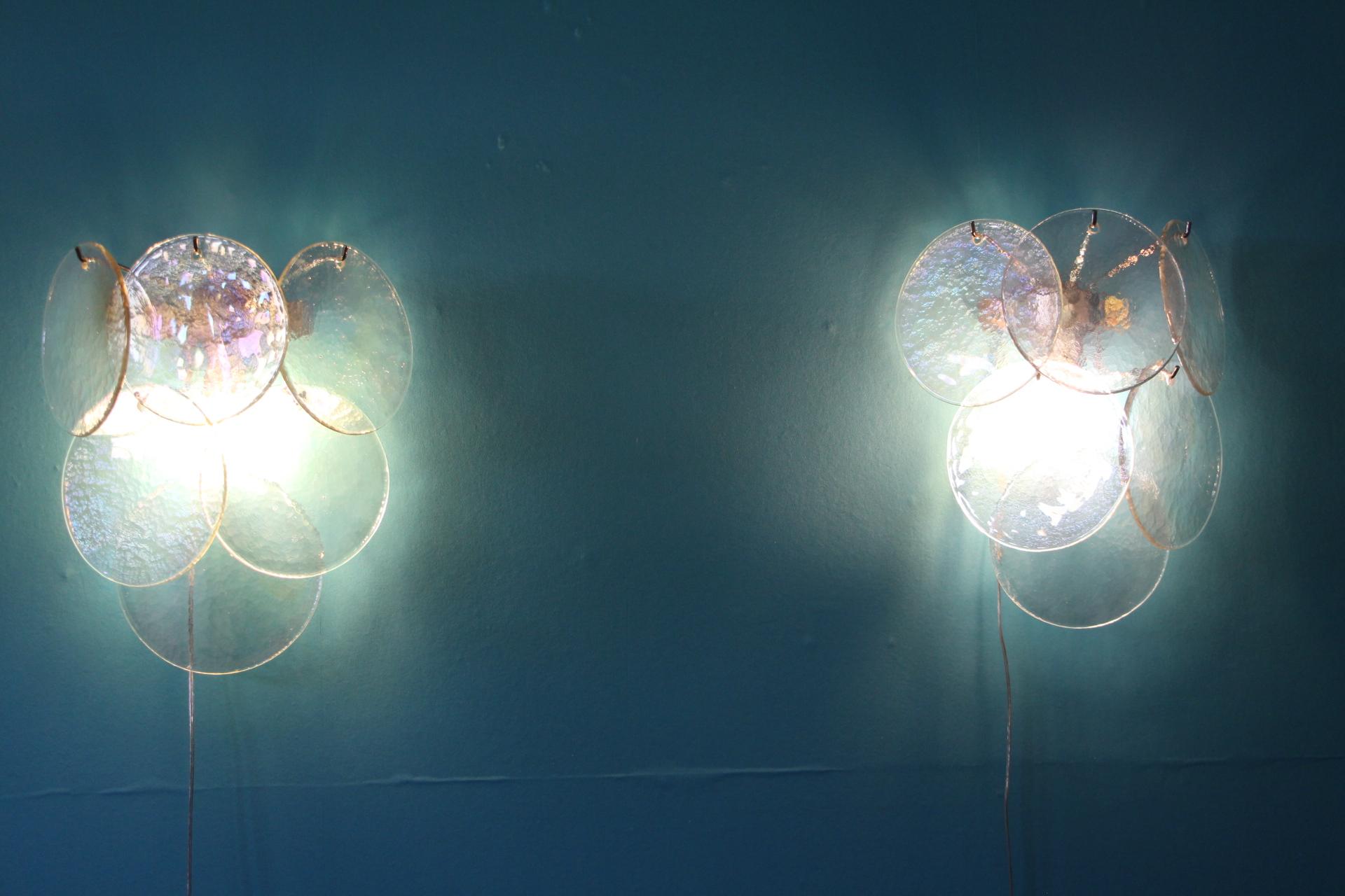 Exquisite pair of geometric structure holding iridescent and pearly Murano glass disks.Each glass disk has got magnificent blue,pink and green reflects 
Very elegant shape and colors.
1 bulb per light.
Take E14bulbs.Wired for the U.SThey are wired