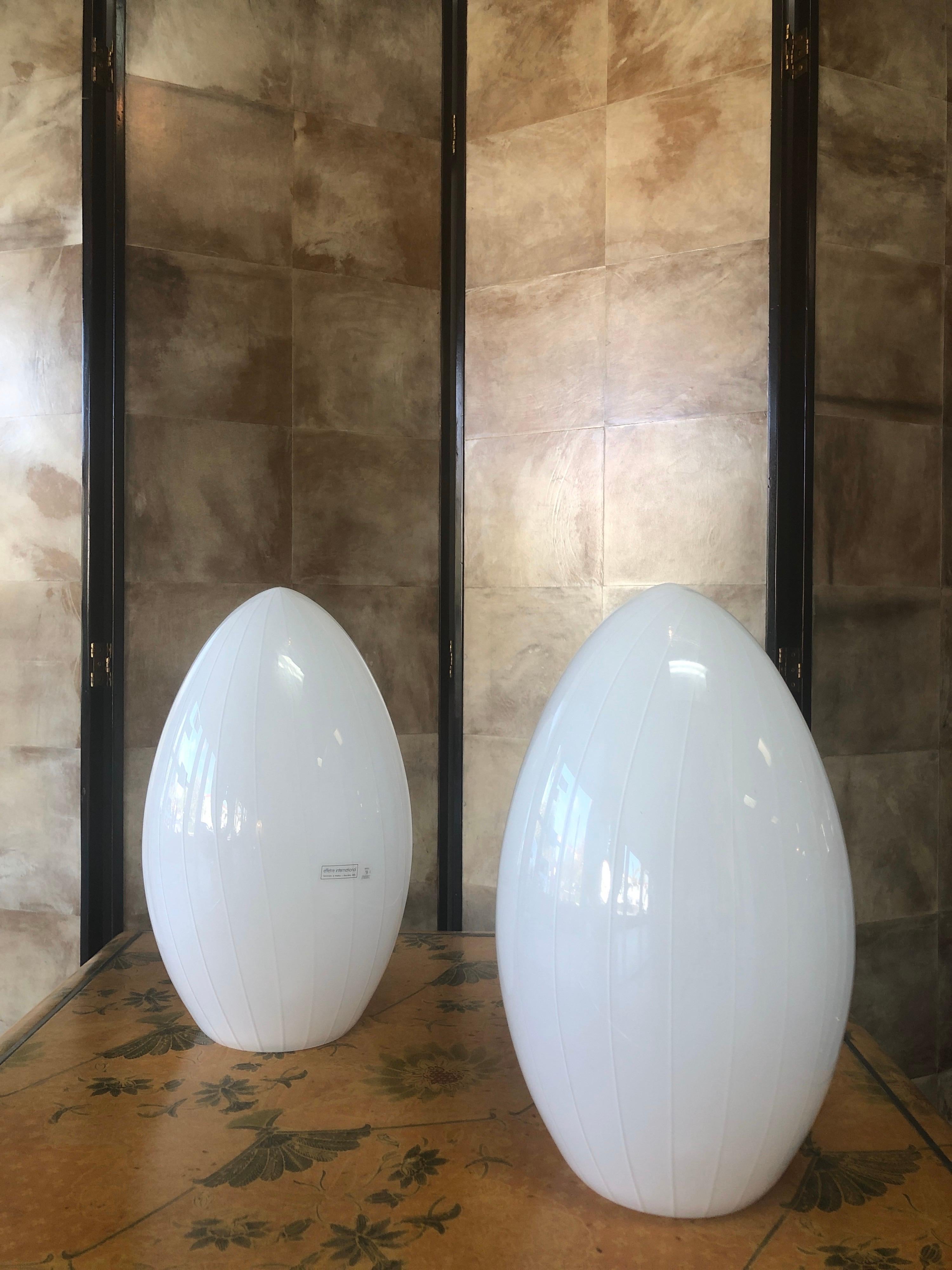 A pair of graceful hand blown Murano art glass table lamps in the shape of an egg with opaque pinstripes going vertically.