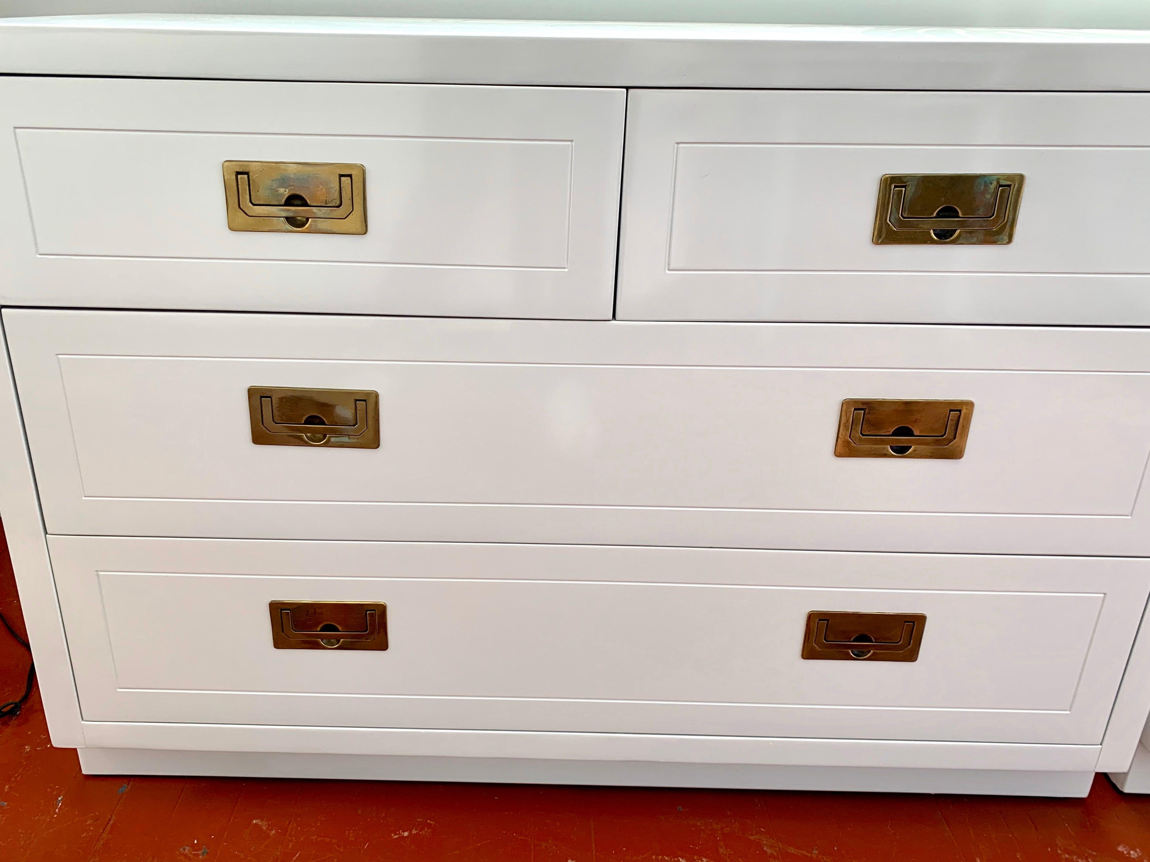 Pair of vintage campaign chests of drawers newly lacquered in white, feature four dovetailed drawers with original recessed brass hardware. Marked “Henredon” inside drawer.