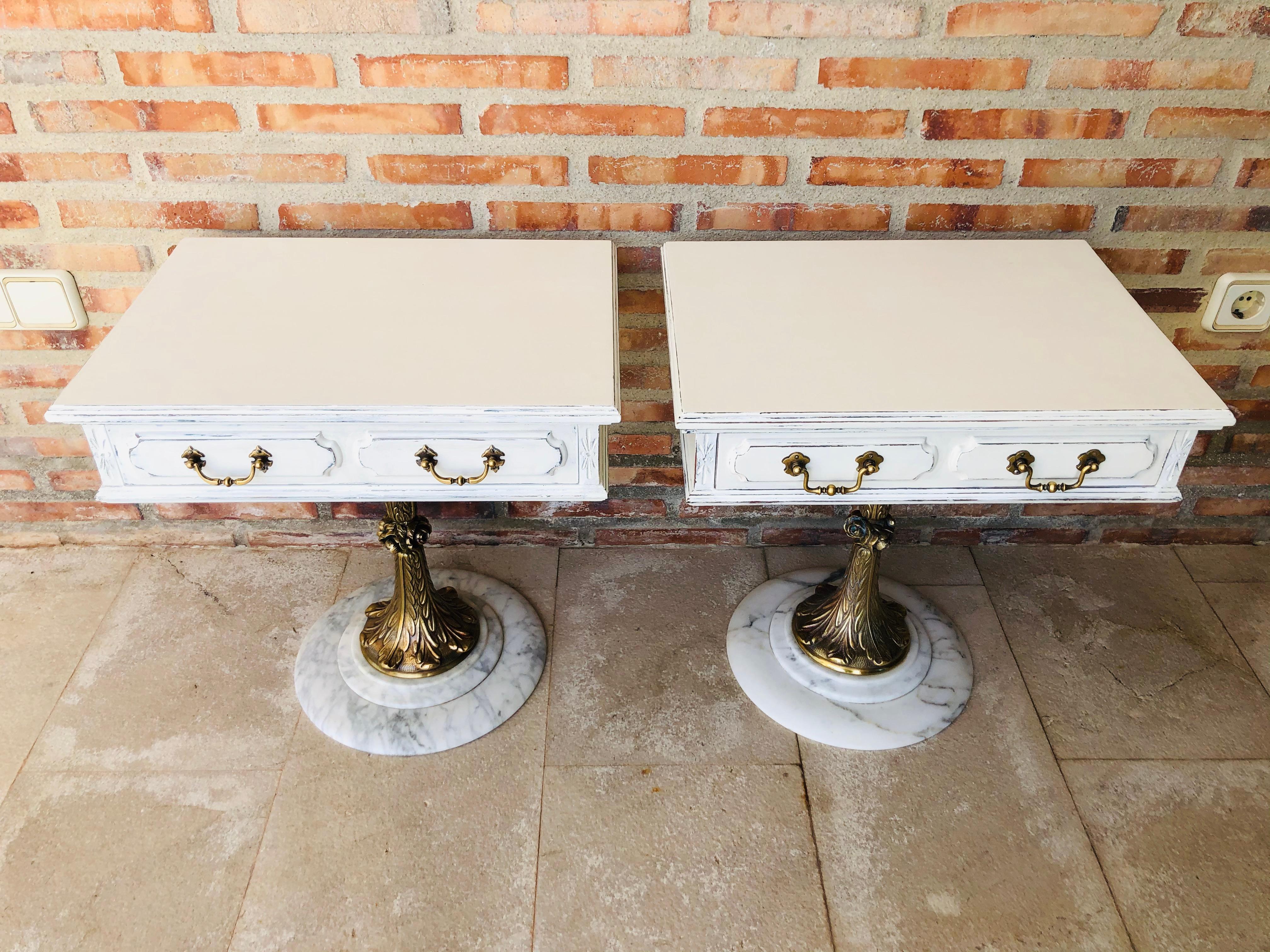 Pair of white nightstands with one-drawer and bronze and marble pedestal.

  