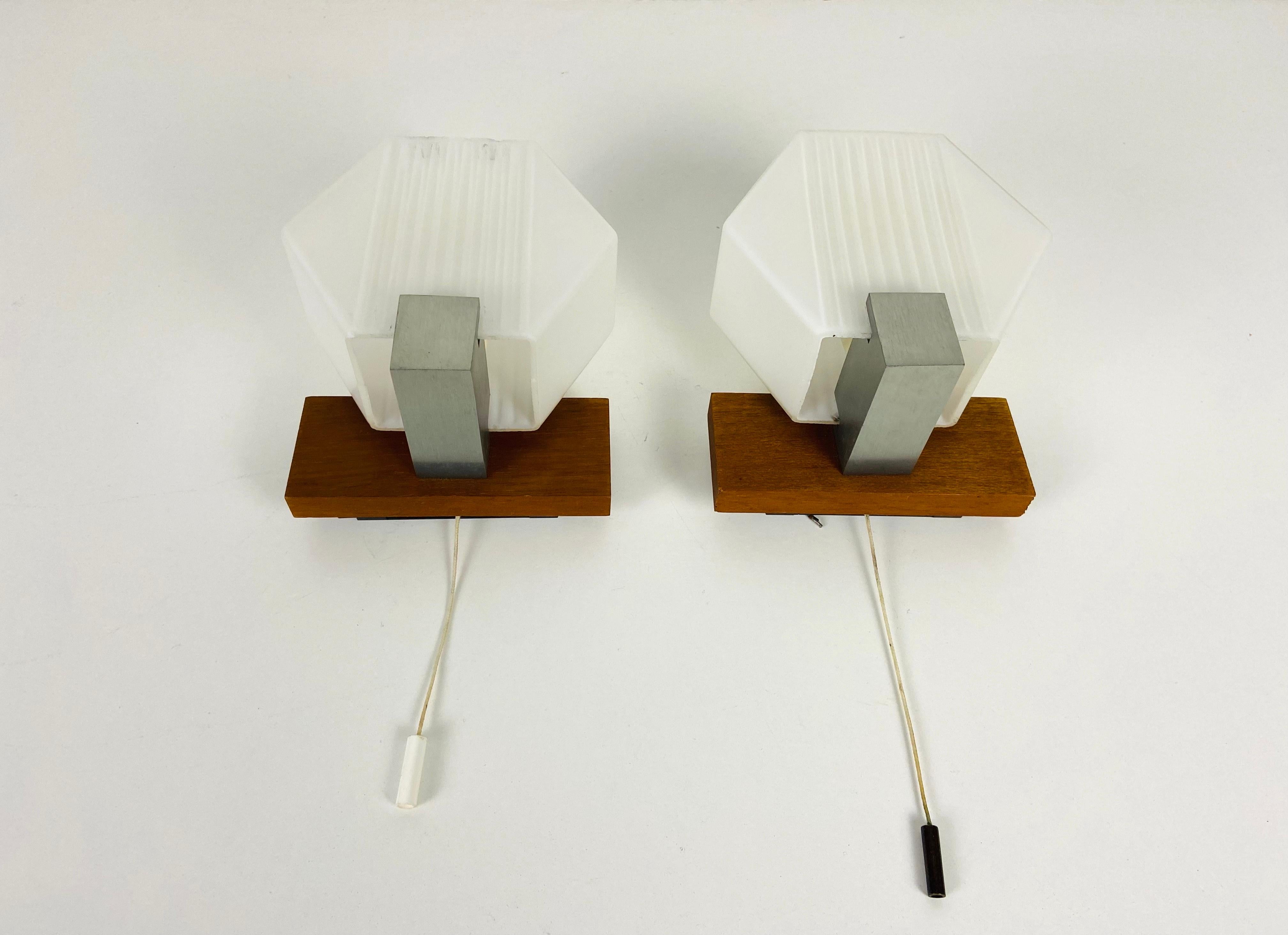 Pair of wall lamps made in Germany in the 1970s. It is fascinating with its glass ornaments. Textured opaline glass with teak body. 

The lights require one E14 light bulb. Works with both 120/220V. Very good vintage condition. Free worldwide