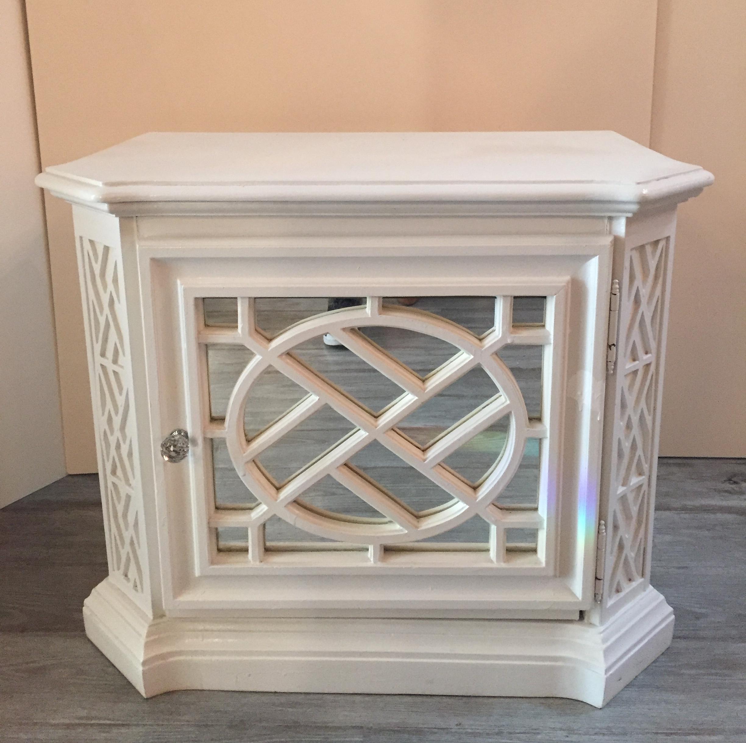 Pair of glamorous white painted nightstand cabinets each having one door with lattice decoration and mirrored background, as well as one interior shelf for storage. The cabinets are Ying & Yang, in other words, the doors open from opposite